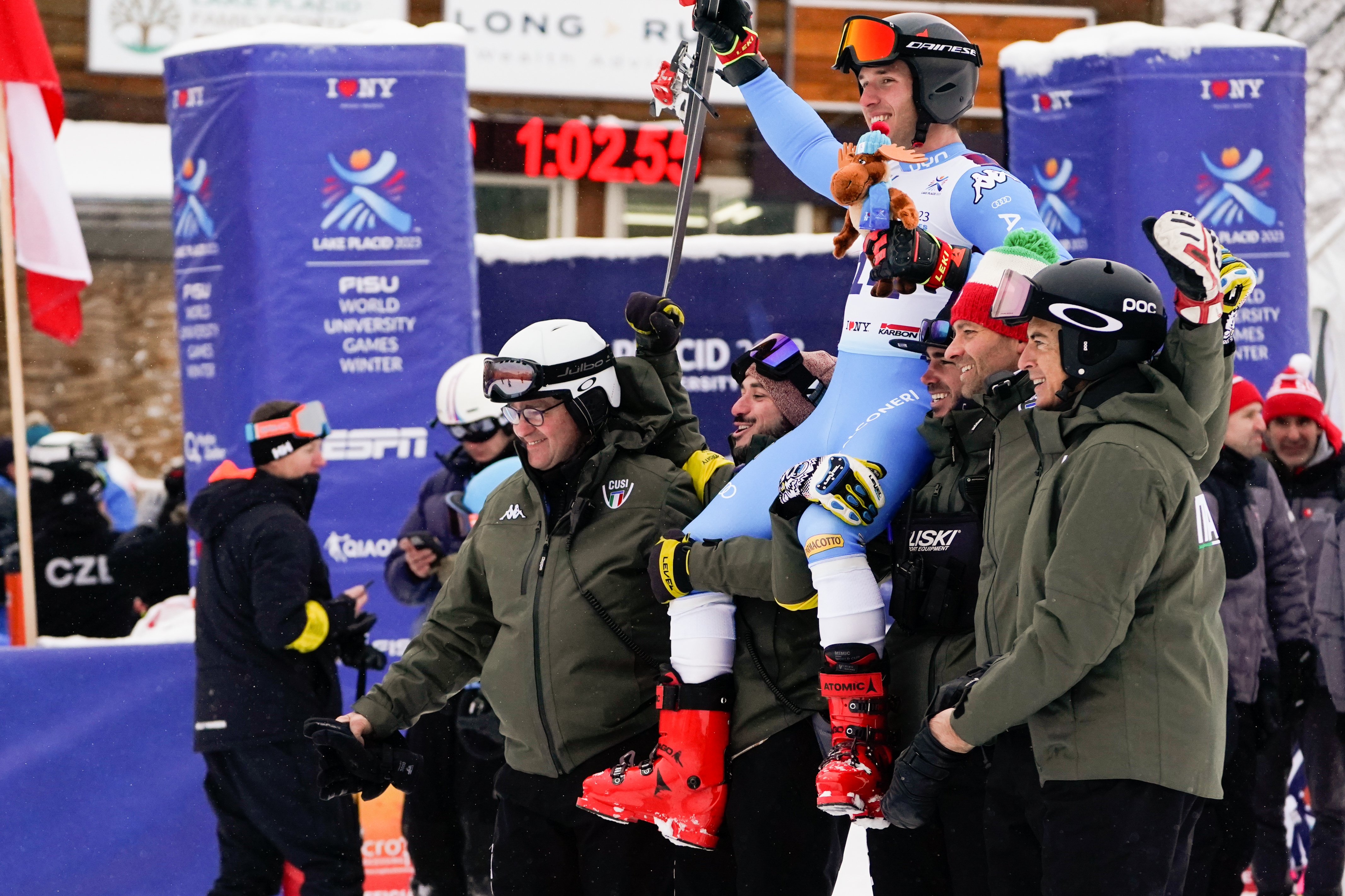 A male Alpine skiier is lifted up on the shoulders of other athletes and coaches after a victory.
