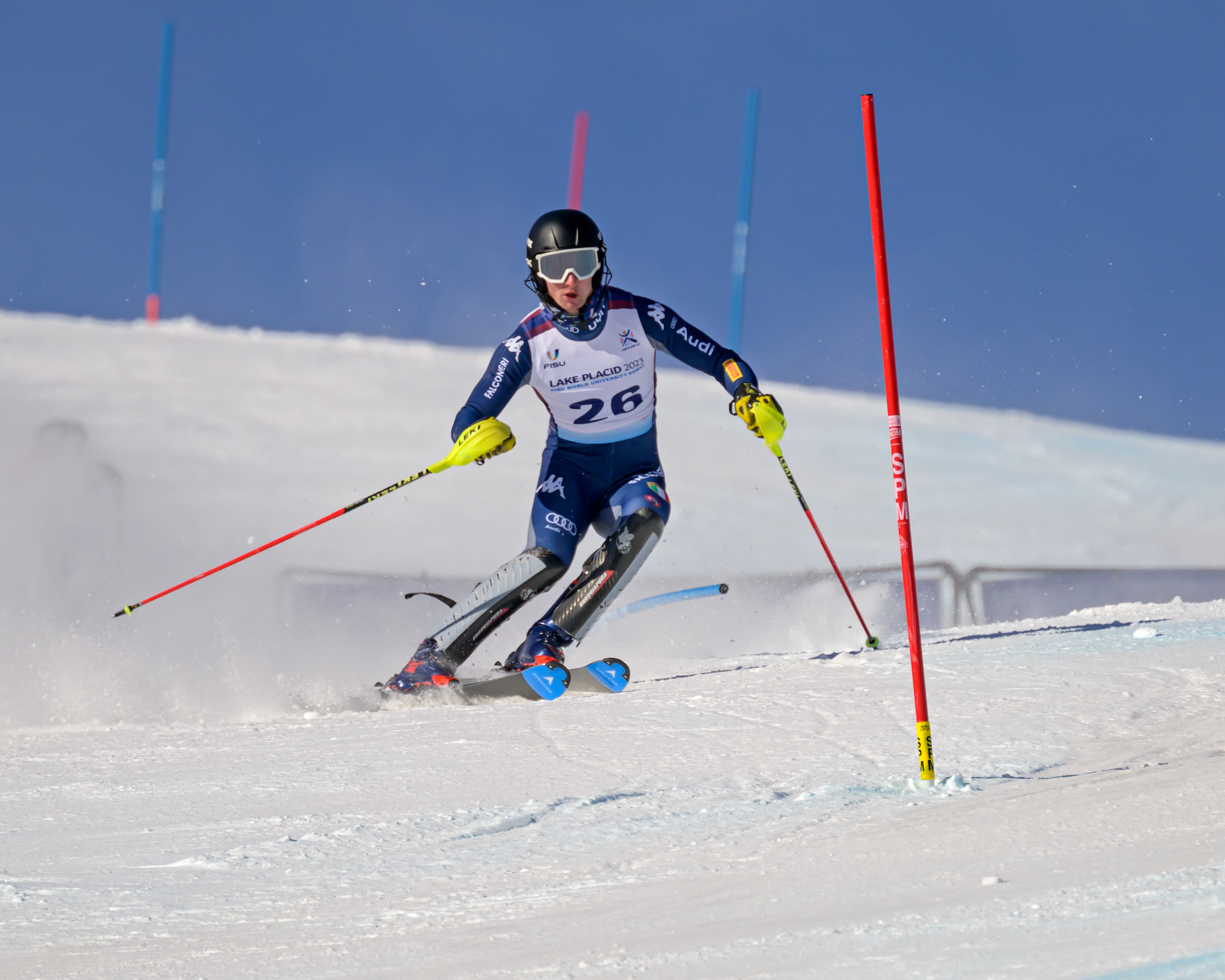 A male slalom skier races down a slalom course on a snowy mountain