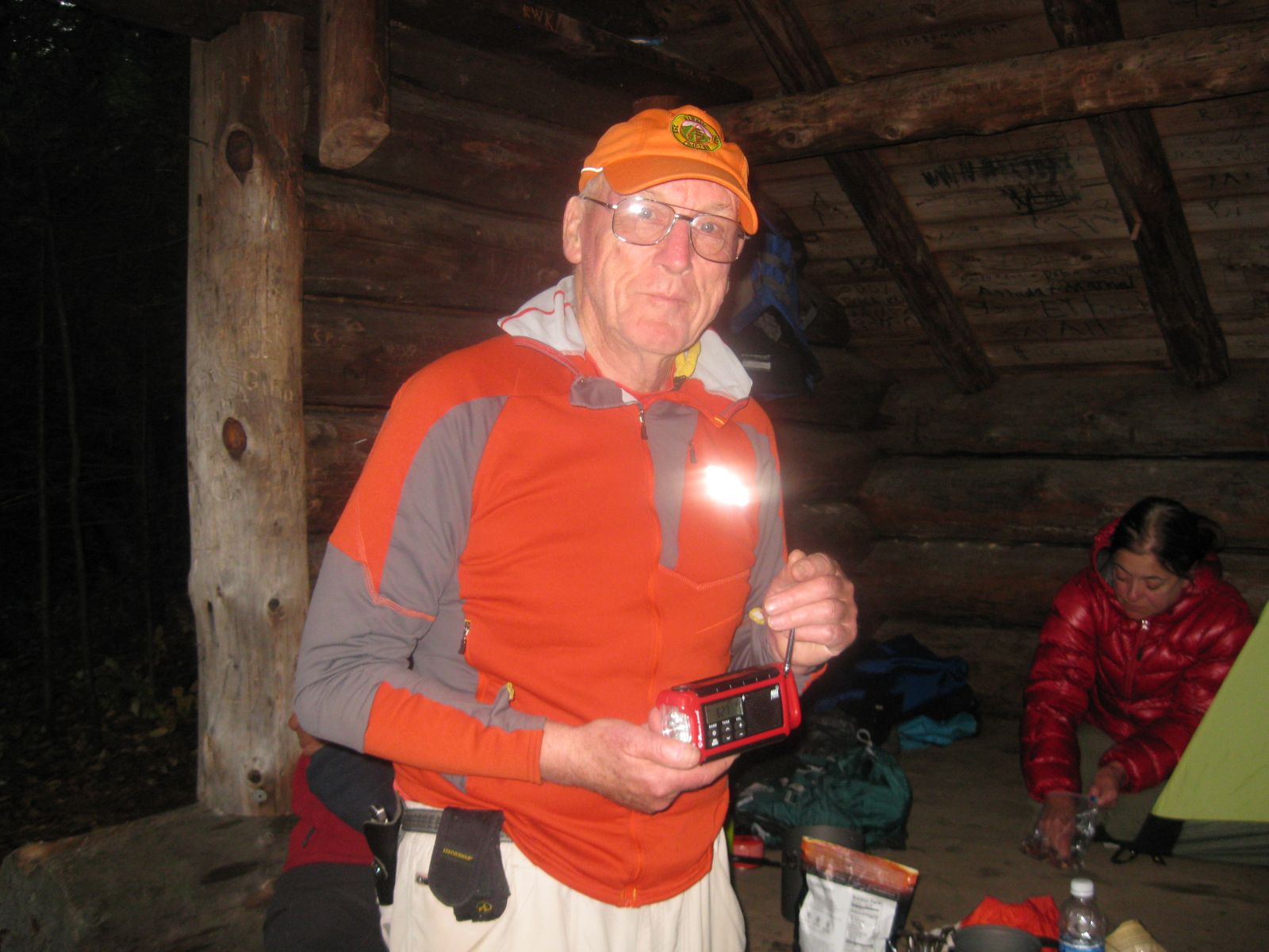 Ed using his weather radio, while Sandra gets organized in the lean-to.