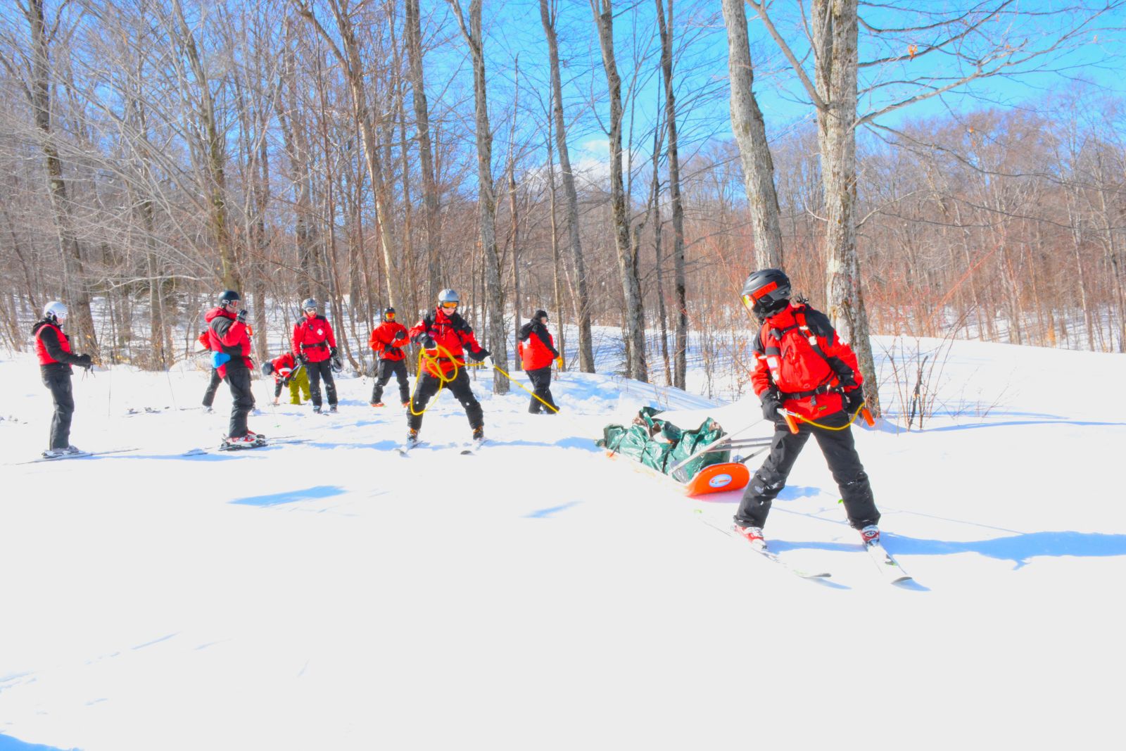 Mitch Harriman, lead sled driver, and Charlie Hoffer,  tail roper, drive the ski patrol sled, with me in the sled, down to the ski patrol building after completing the second training scenario.