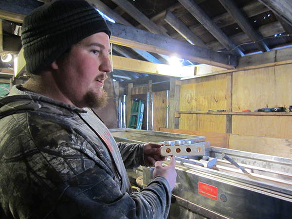 Owner Kevin Sayre displays sample bottles of syrup grades.