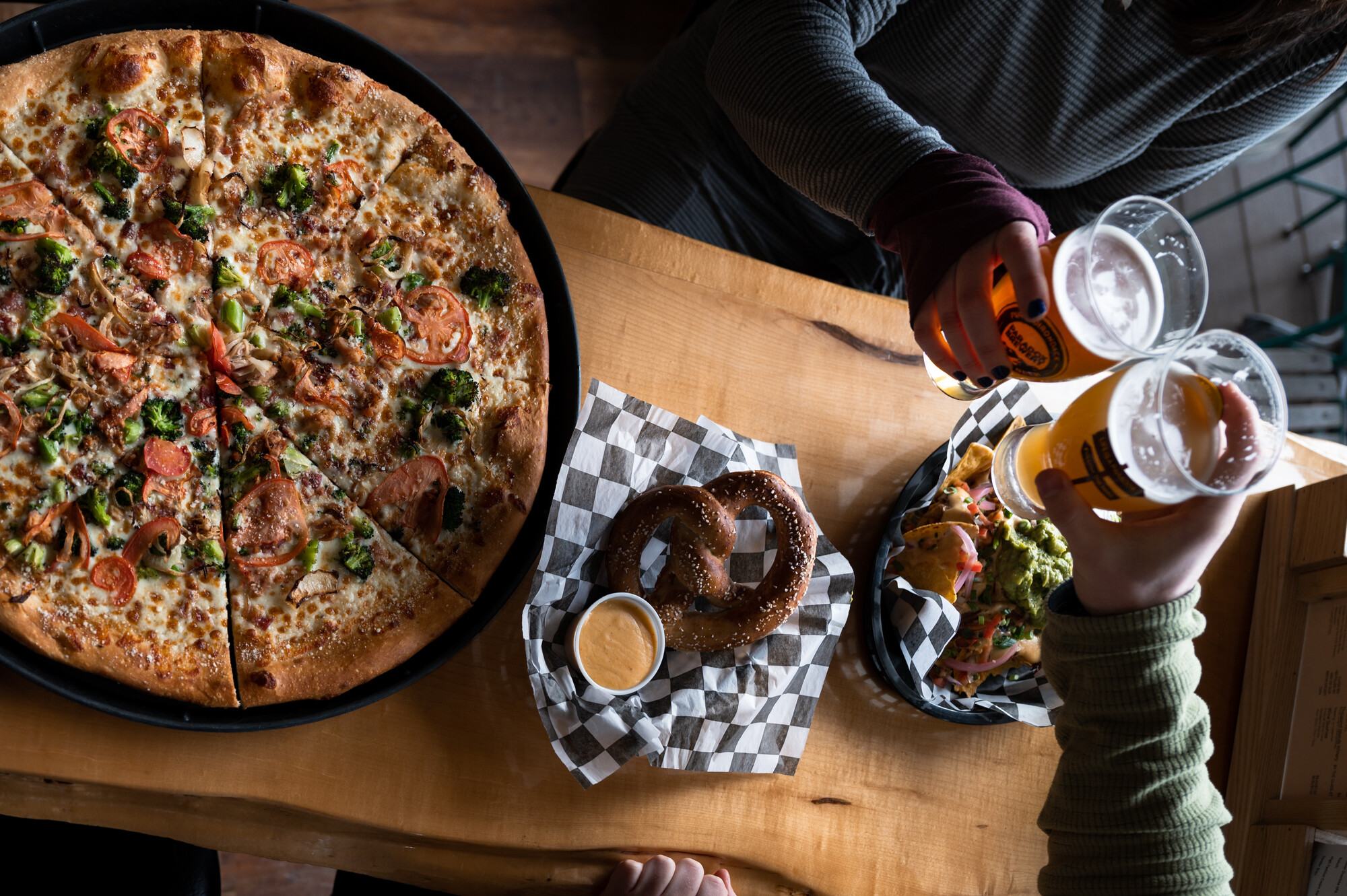 A table spread of pizza, pretzel, and beer