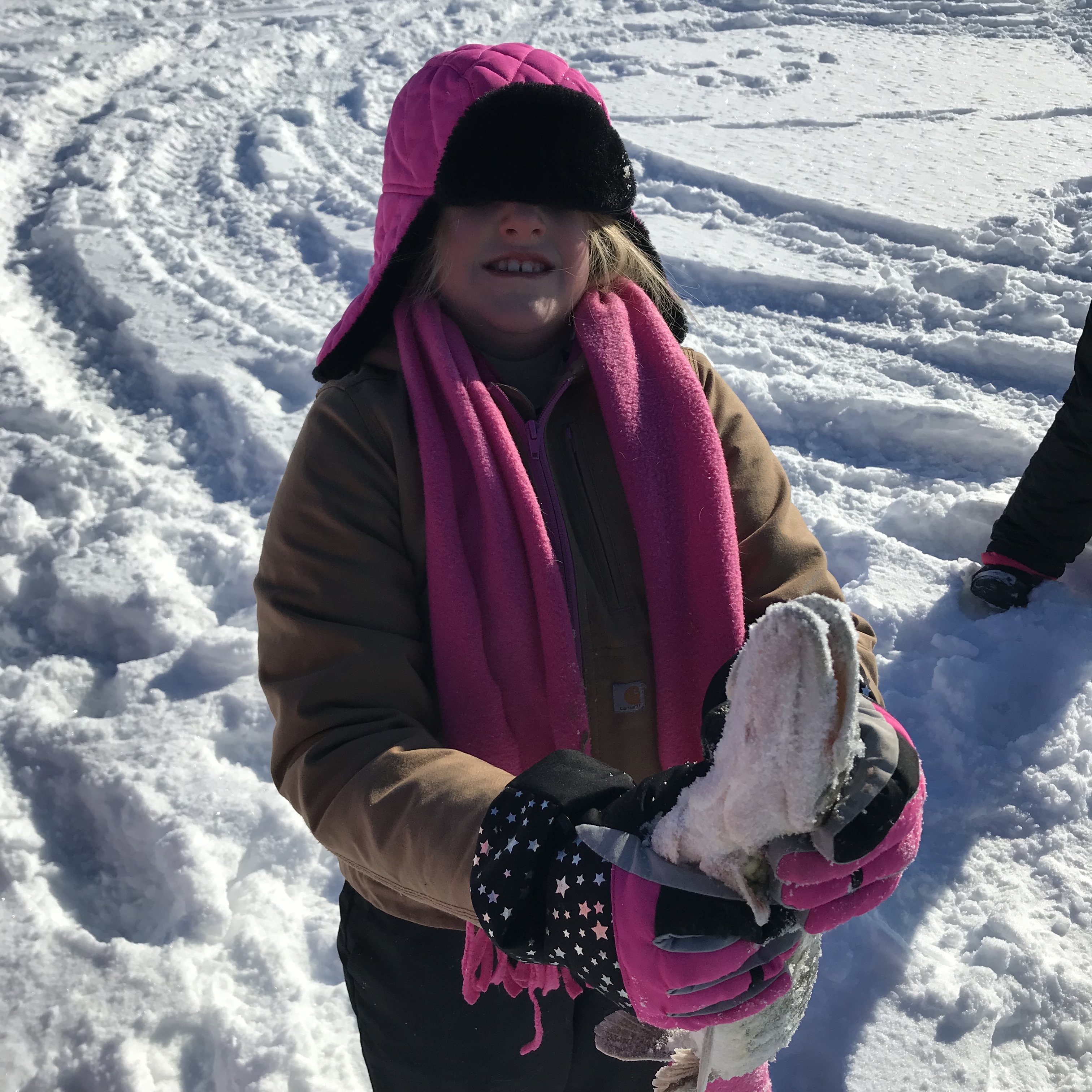 image of a girl in a pink scarf and winter wear showing off a large snowy fish