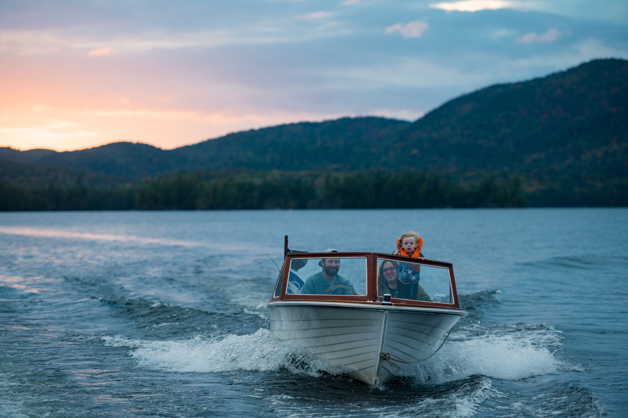 A man, woman, and child look out as they ride on boat.