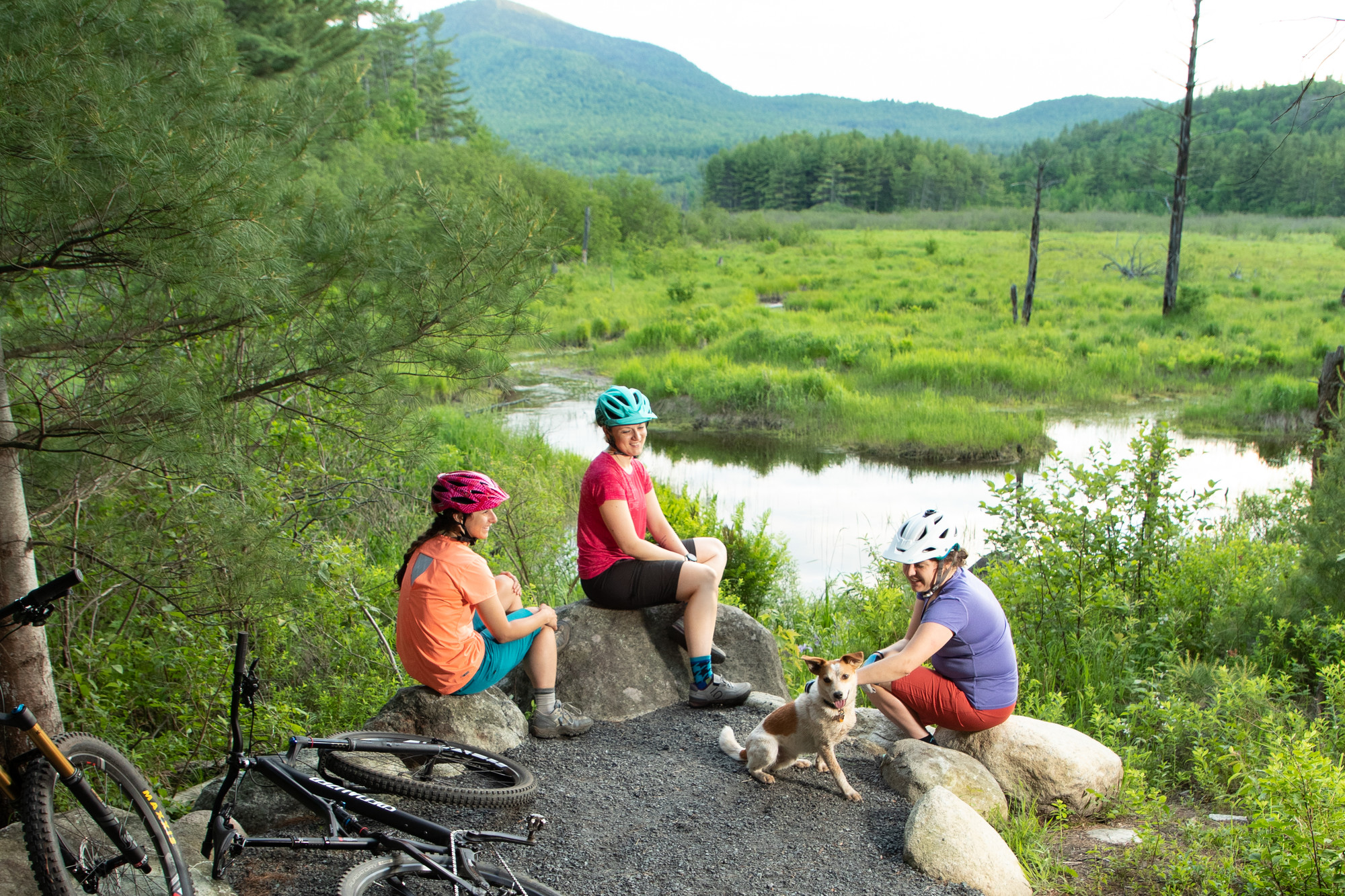 Group of women sitting on rocks overlooking the river for a bike break.