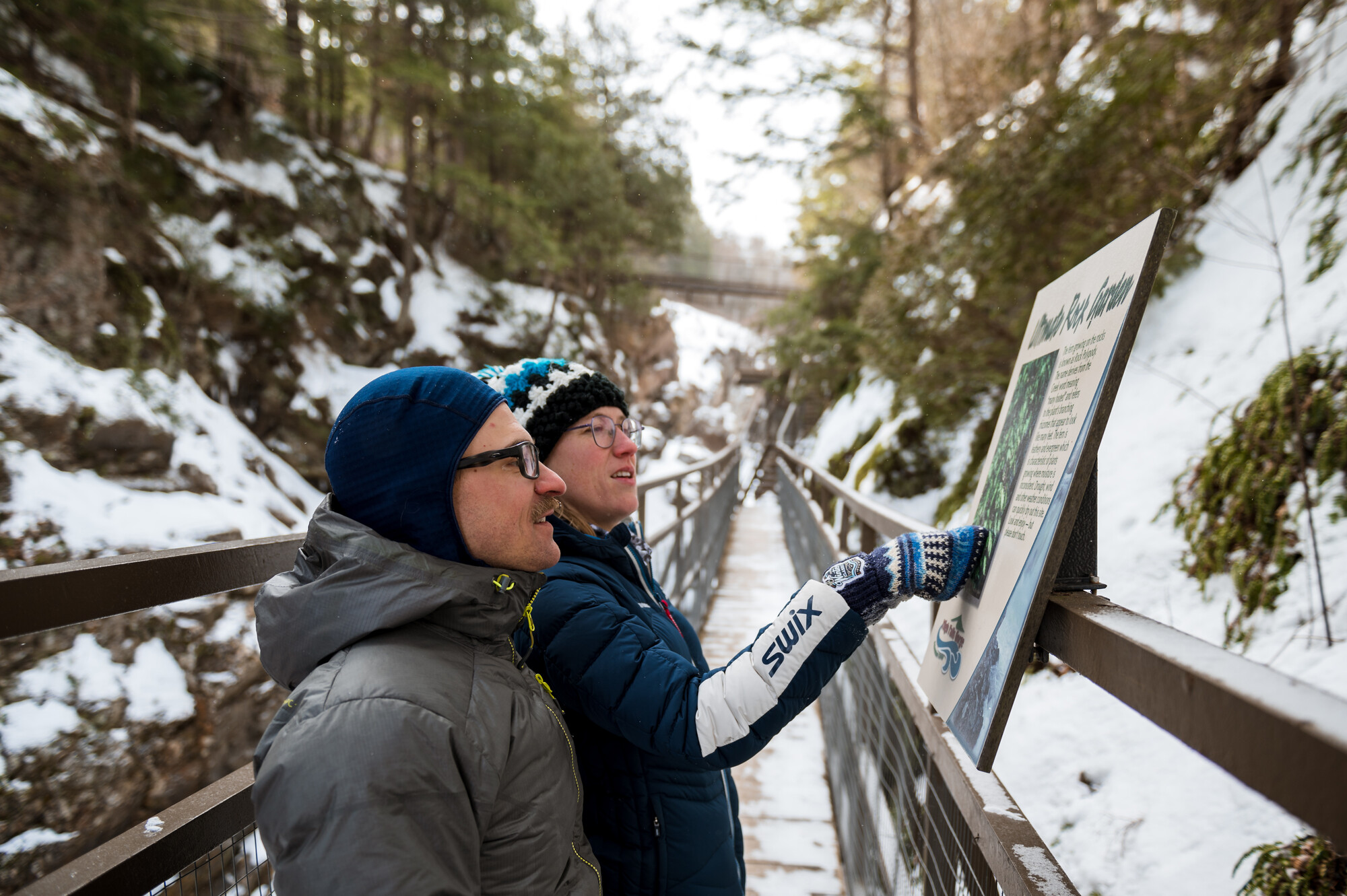 A couple pointing and looking at a sign while on a walk at High Falls Gorge.