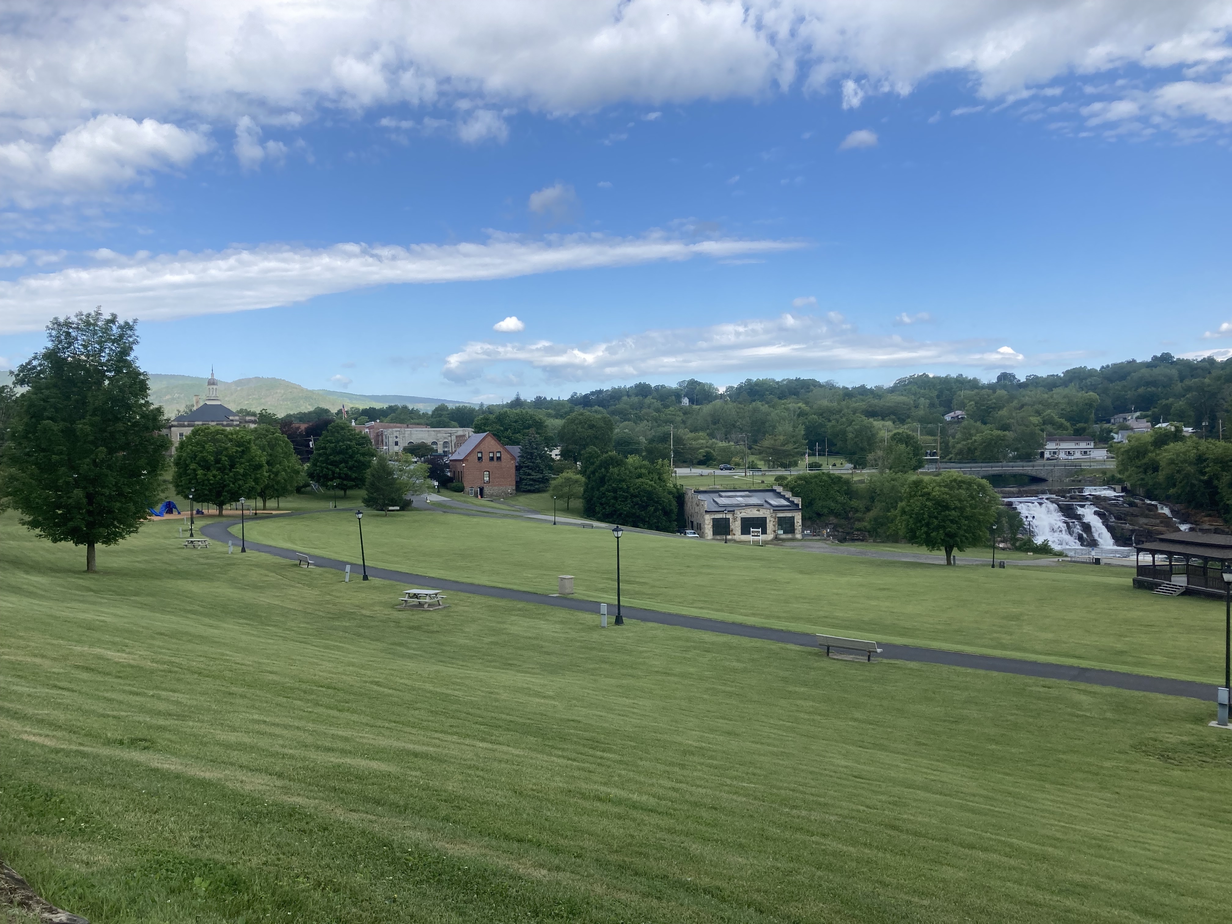 A wide view of a grassy park with historic buildings in the background.