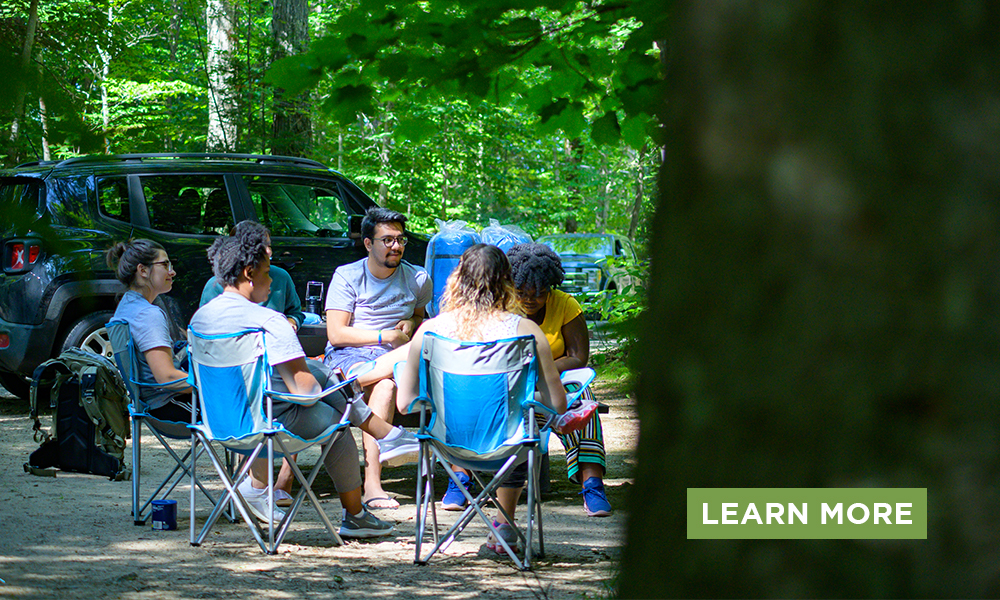 A group sits around a campfire while camping in the Adirondacks.