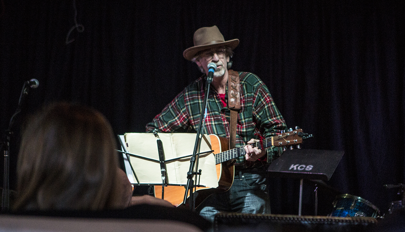 A man in a hat performs for an audience