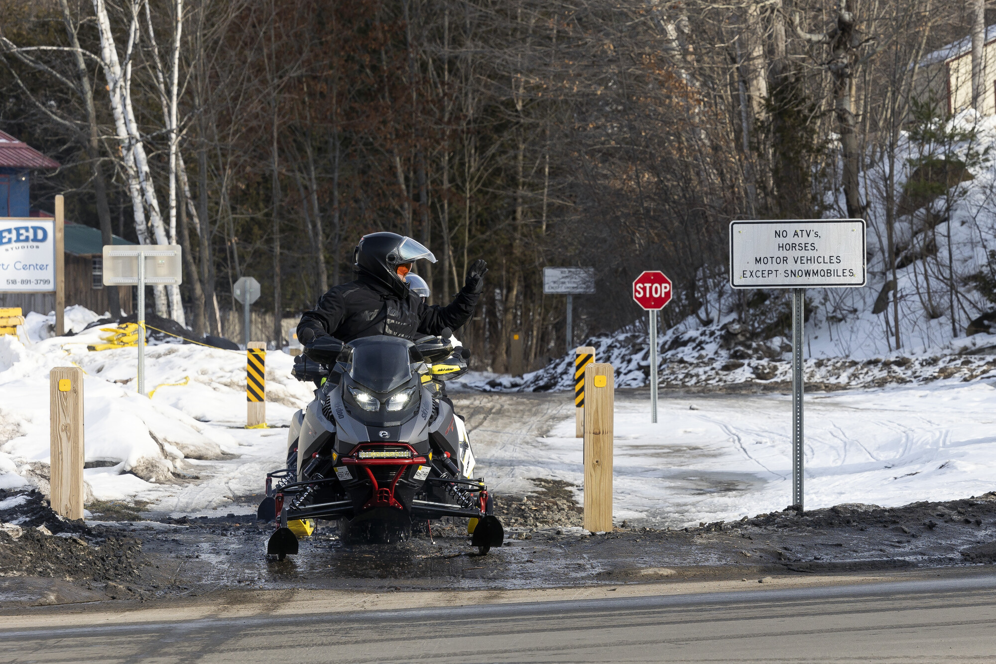 Snowmobilers look both ways before crossing a road