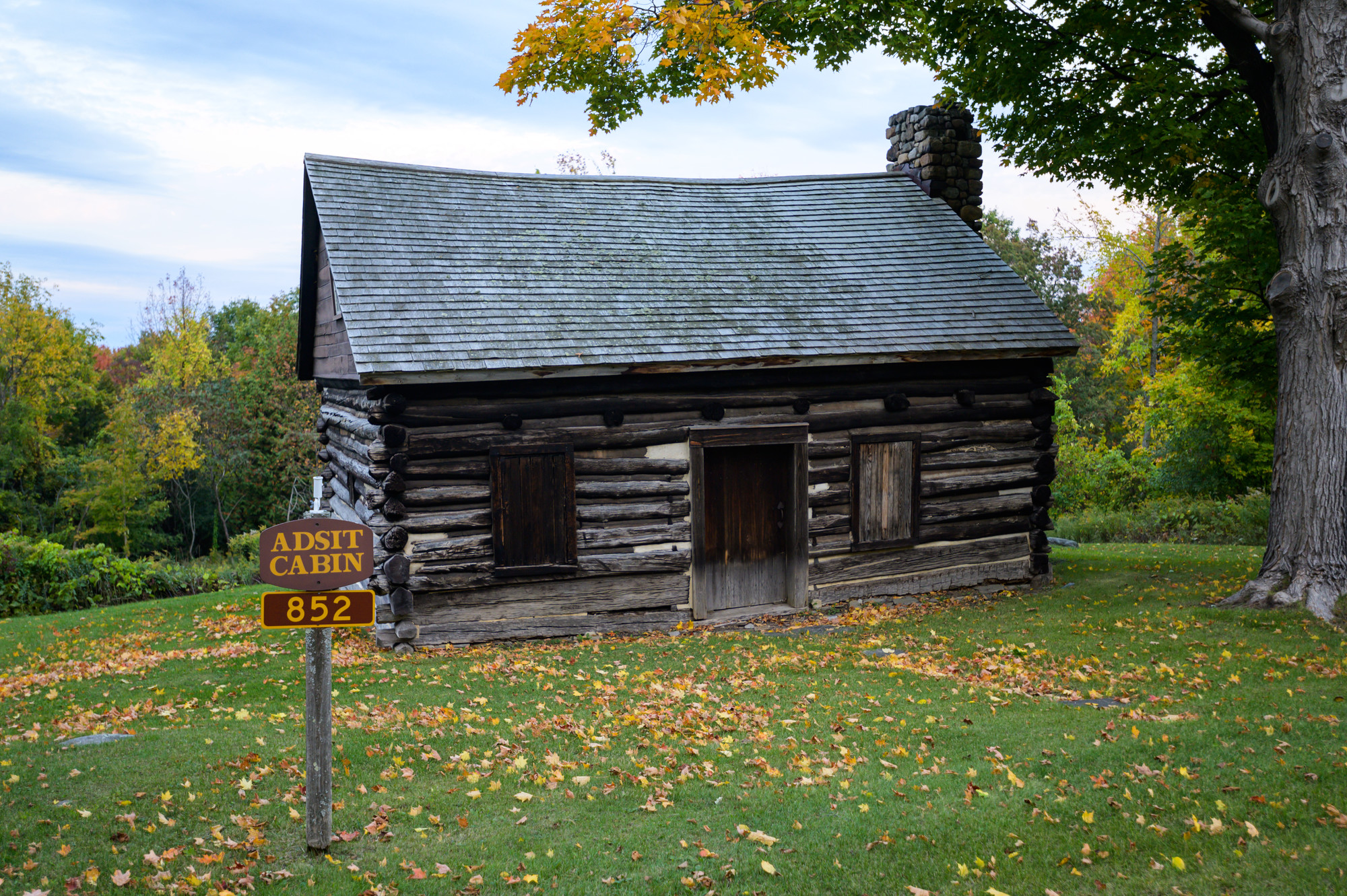 Admit Cabin from the outside, with fall leaves on the ground.