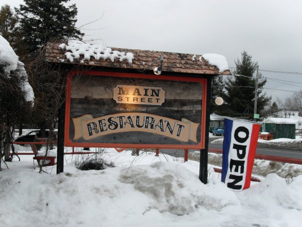 A restaurant sign in the snow. 