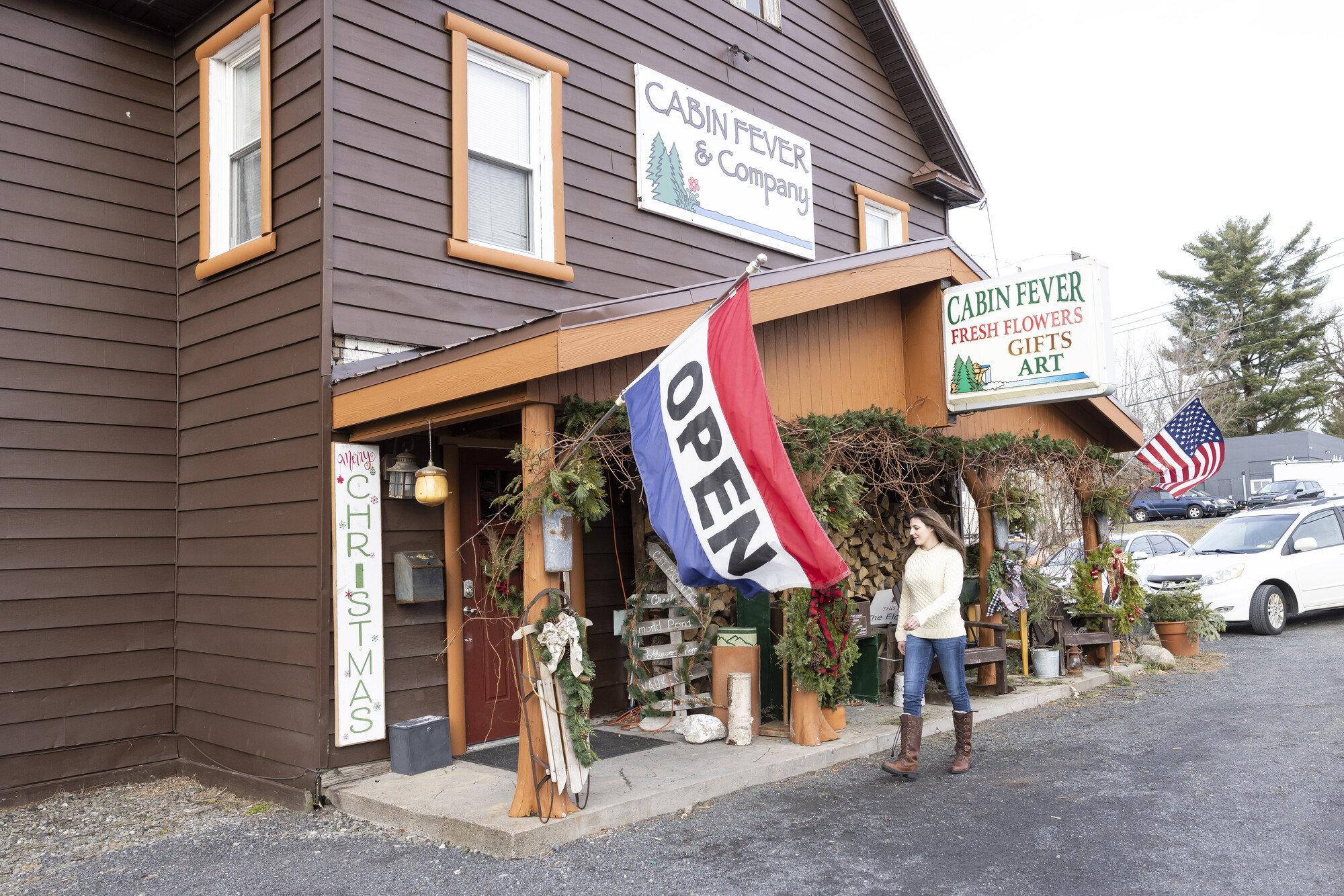 A woman walks into a cabin-style floral shop.