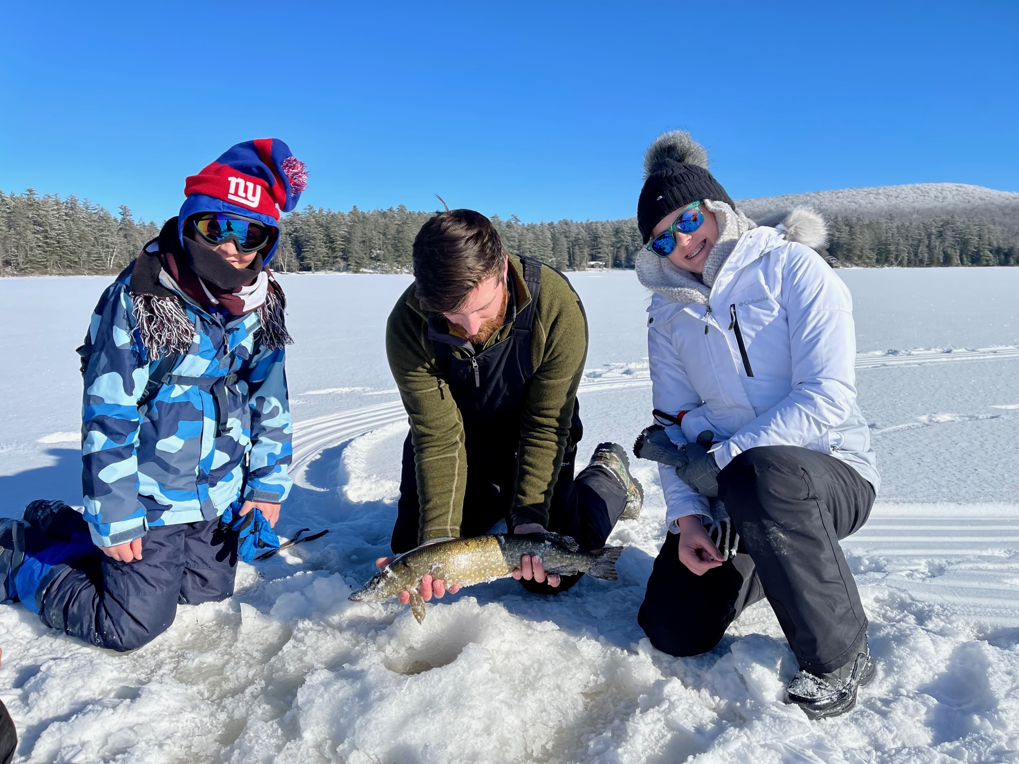 A group of three gathers around the most recent catch.