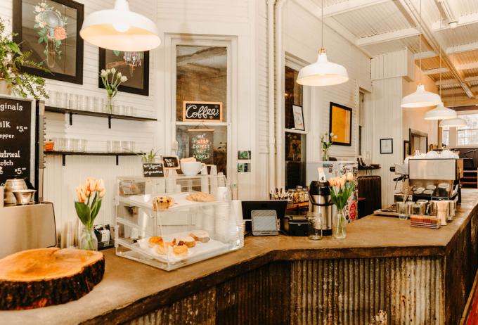 Origin can compete with larger chain style coffee shops no matter what season it is A coffee shop with a rustic bar with desserts and hot drink machines.