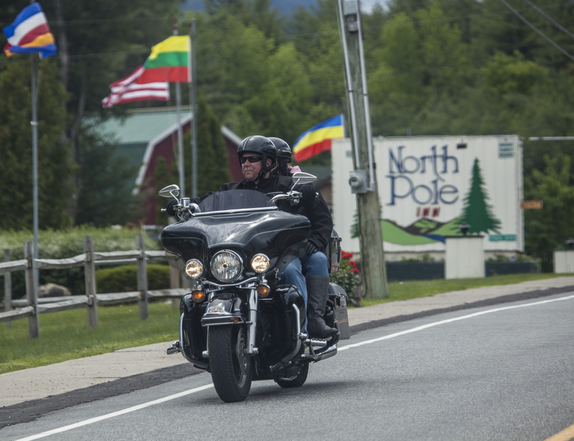 A couple on a motorcycle riding with a retro motel sign in the background.