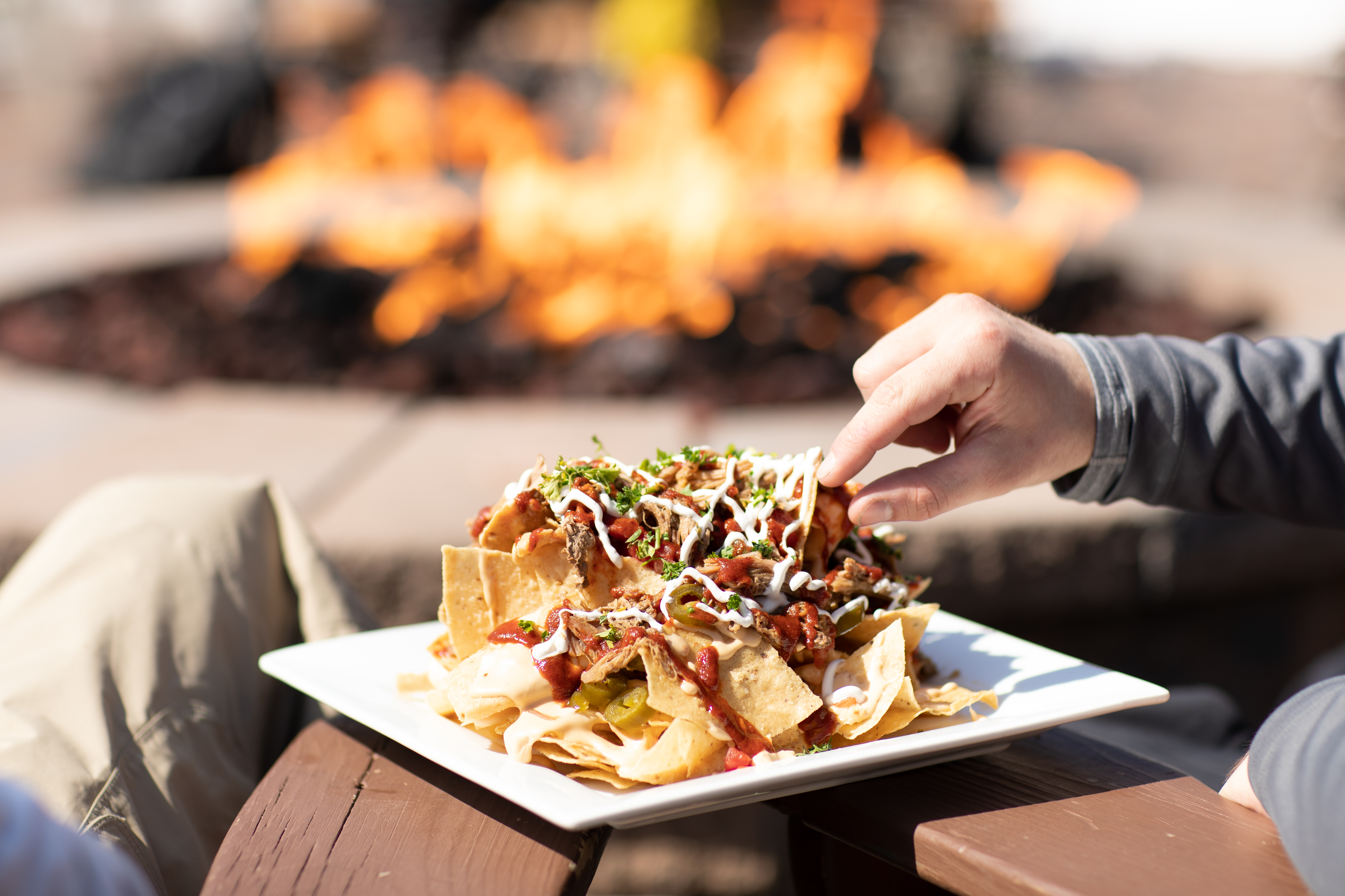 A person eats nachos on a deck.