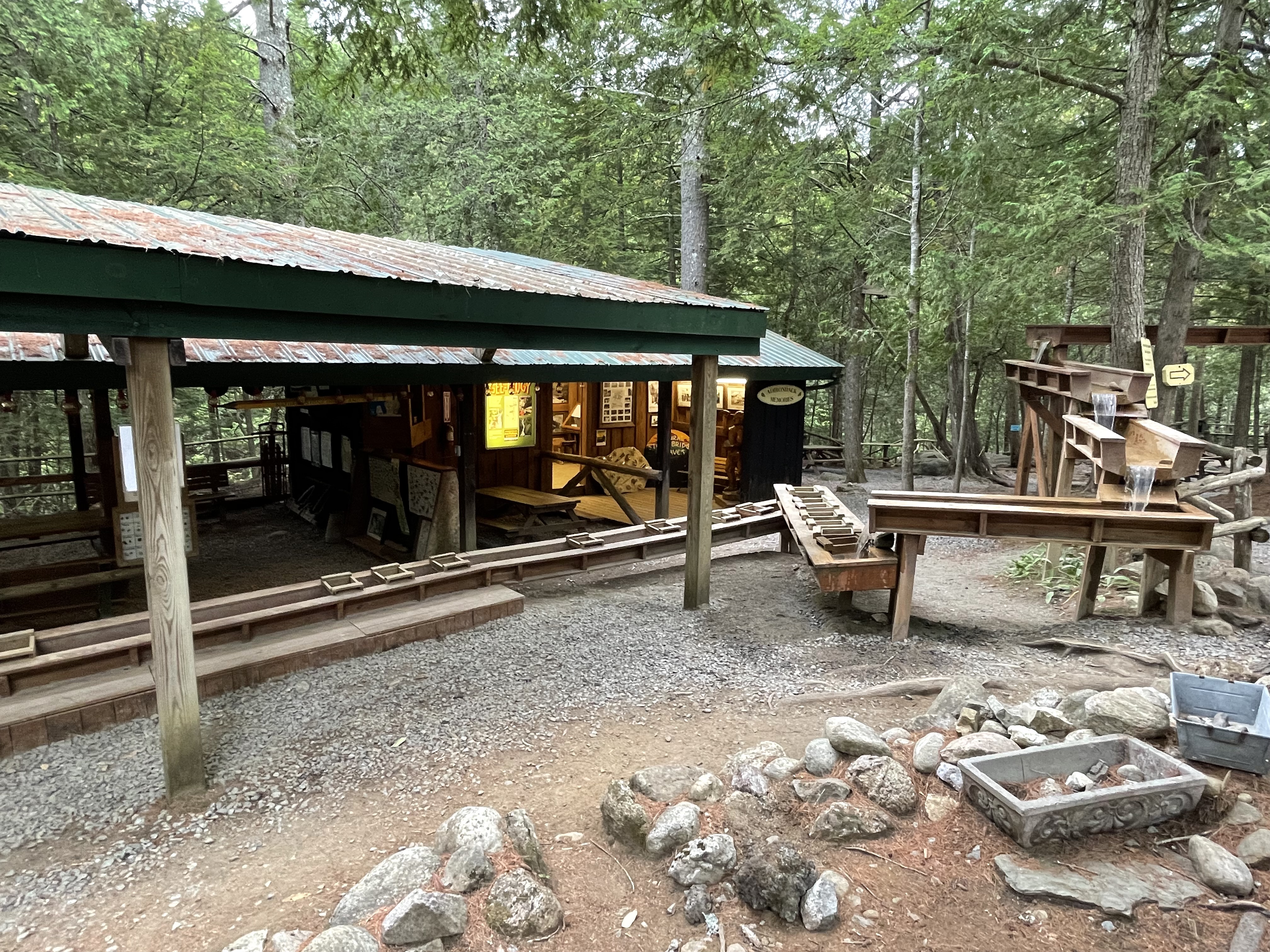 An outdoor wooden sluice in front of a covered "gem mining" activity for children.