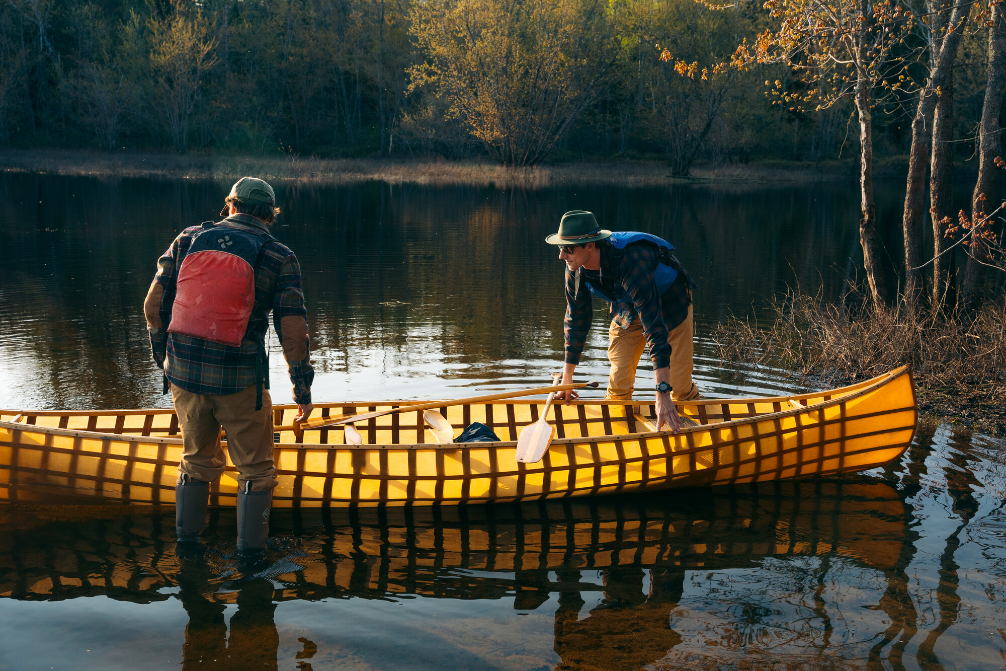 Two paddlers launch their boat into the water