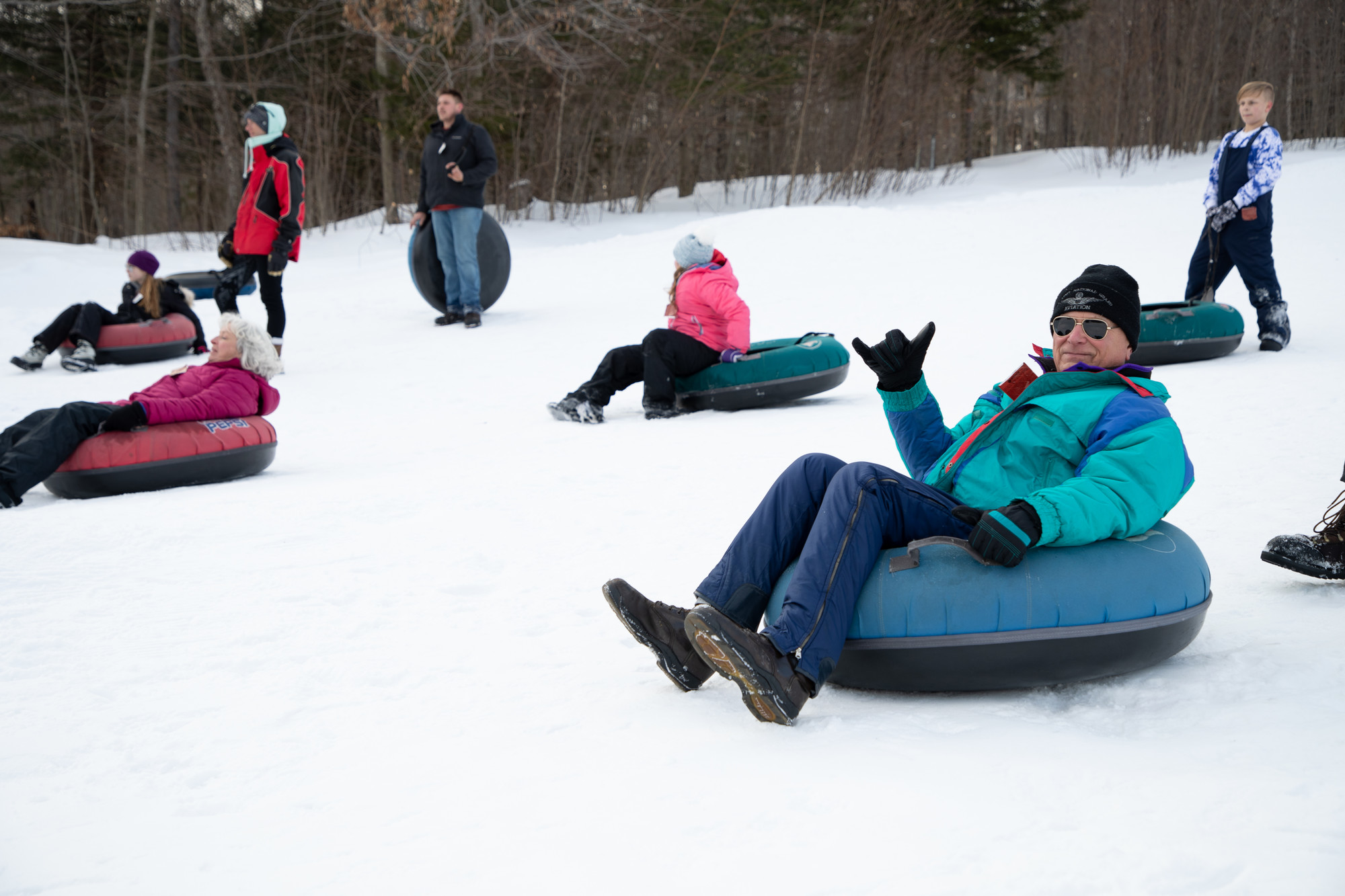 a man tubes down a hill with others.