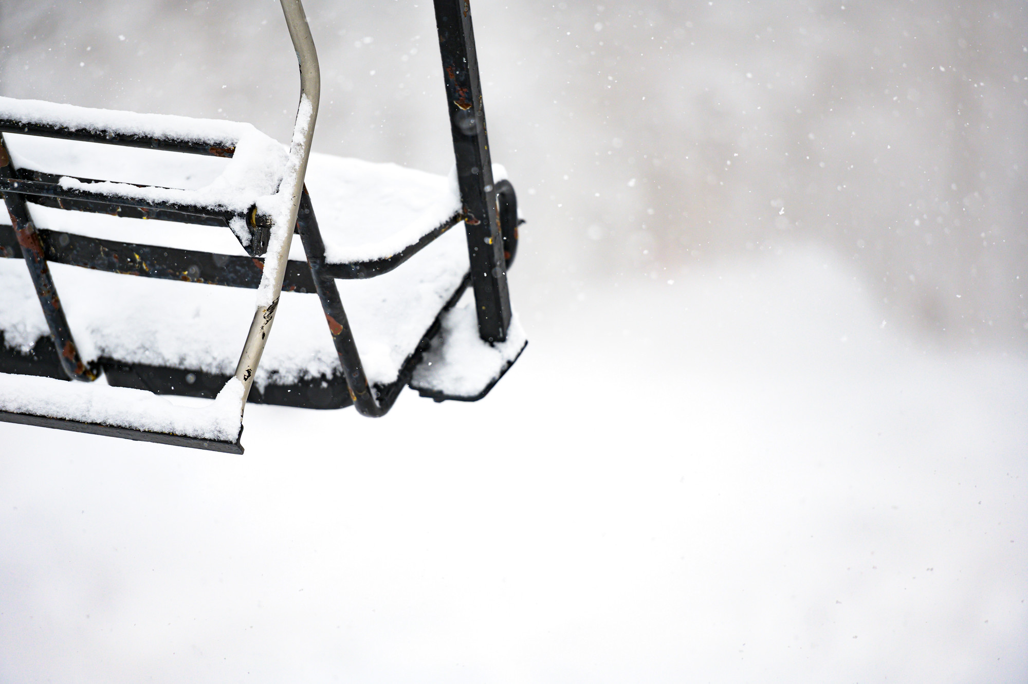 Snow built up on a stationary chair on a lift.