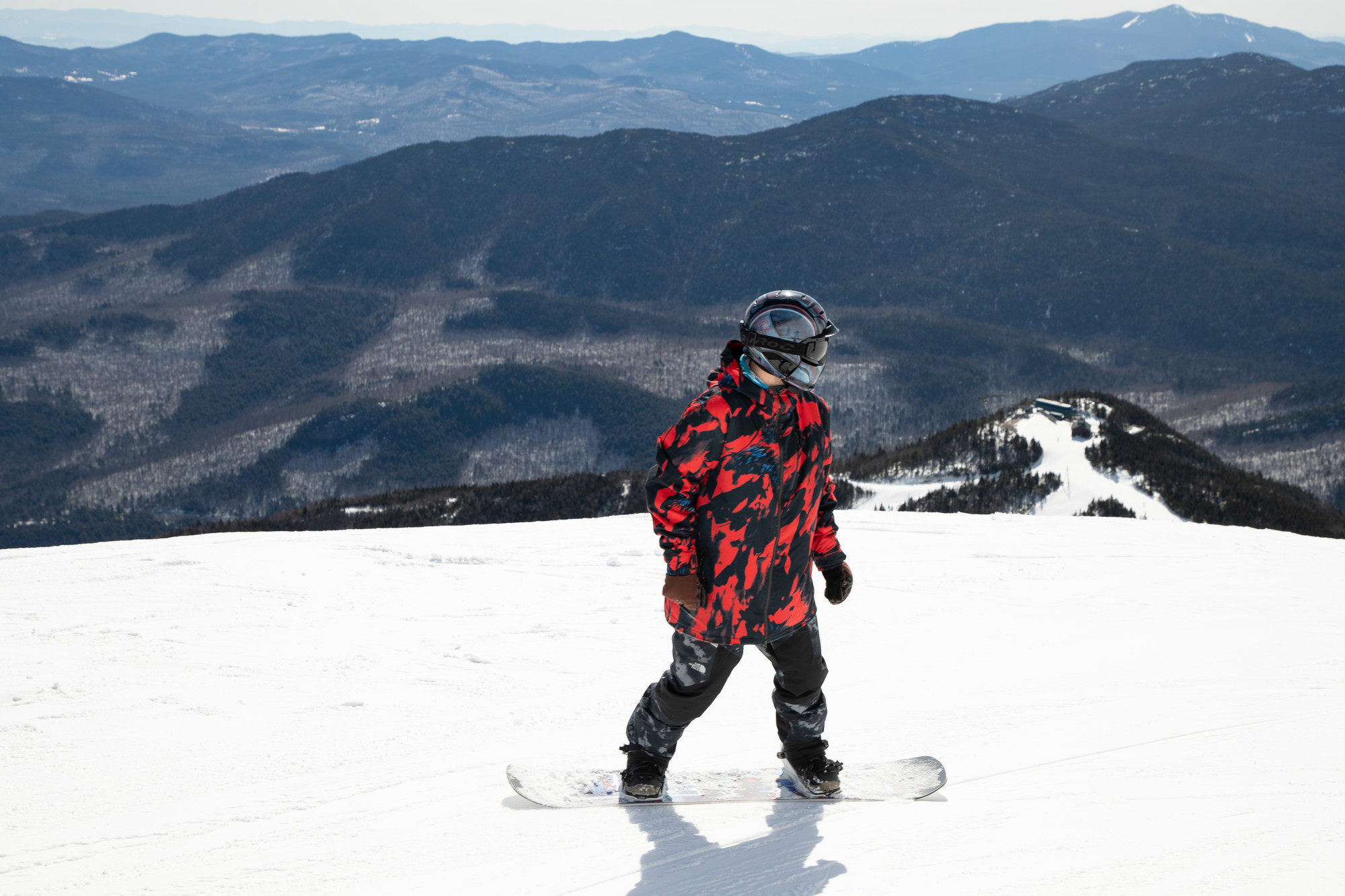 A snowboarder on the summit of Whiteface looking down at Little Whiteface below.