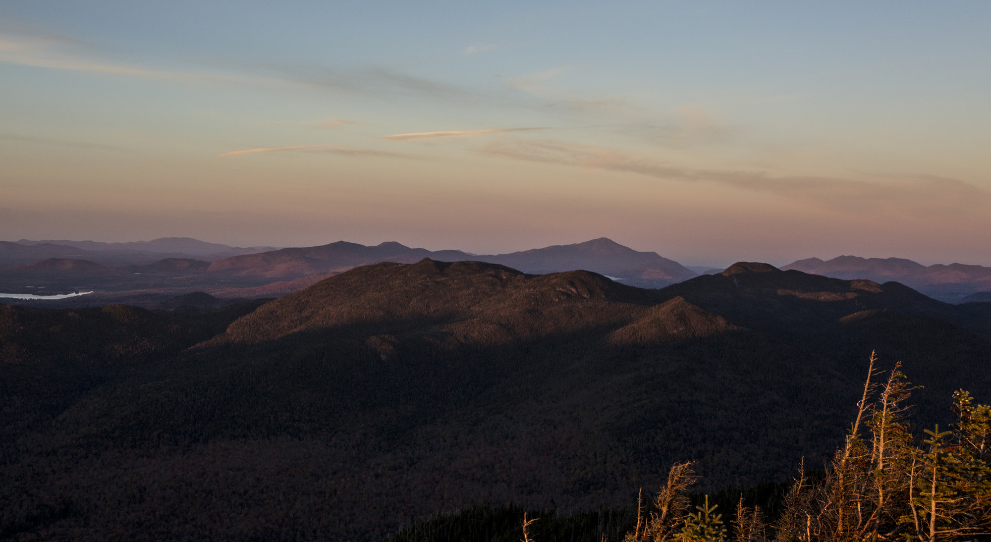 A colorful sunset overlooking tall, tree-covered mountains