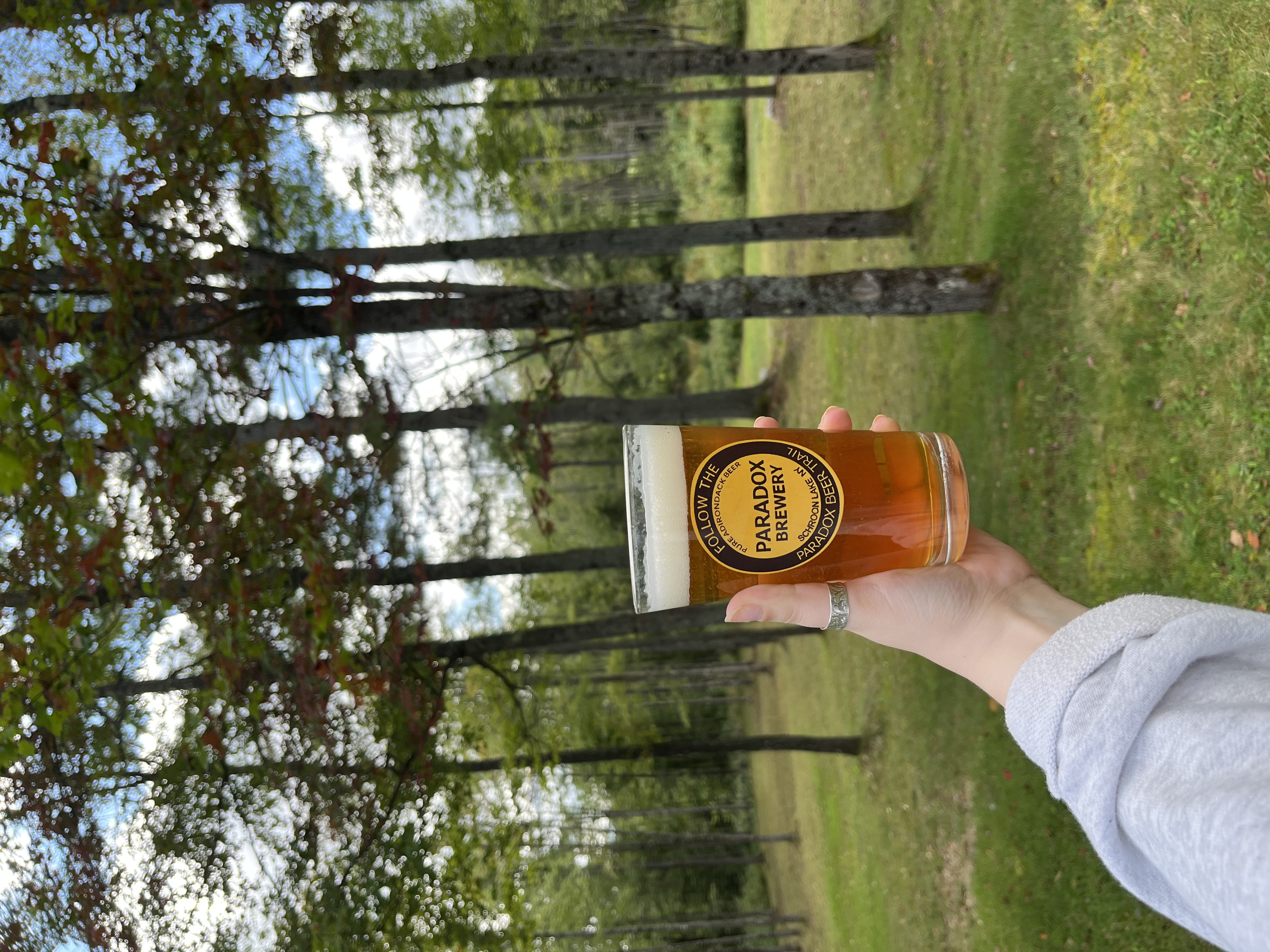 A person's hand holds a paradox brewery beer in a paradox brewery glass
