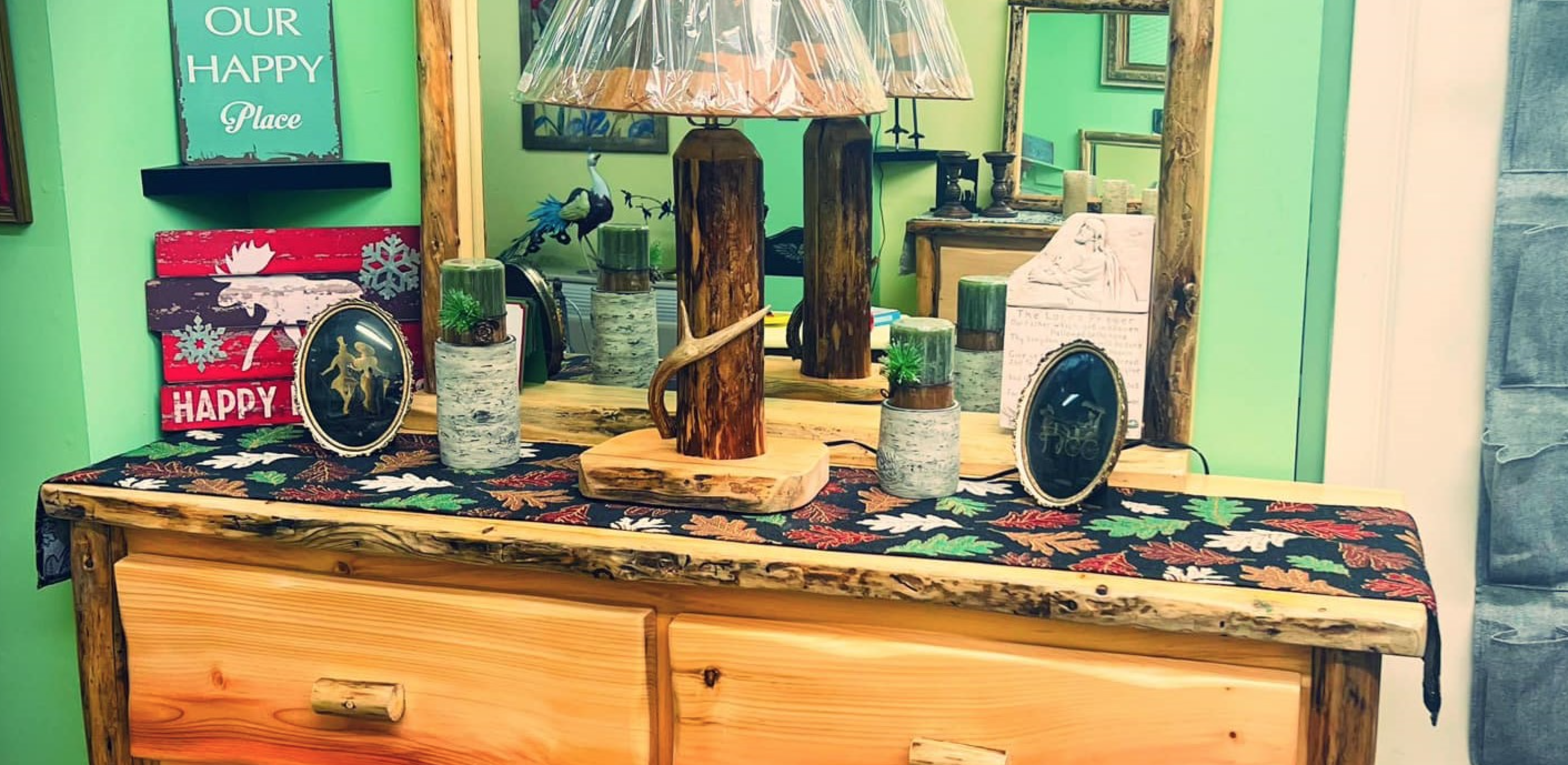 A rustic wood dresser displays birch decor, rustic lamp, and small framed pictures in a shop.