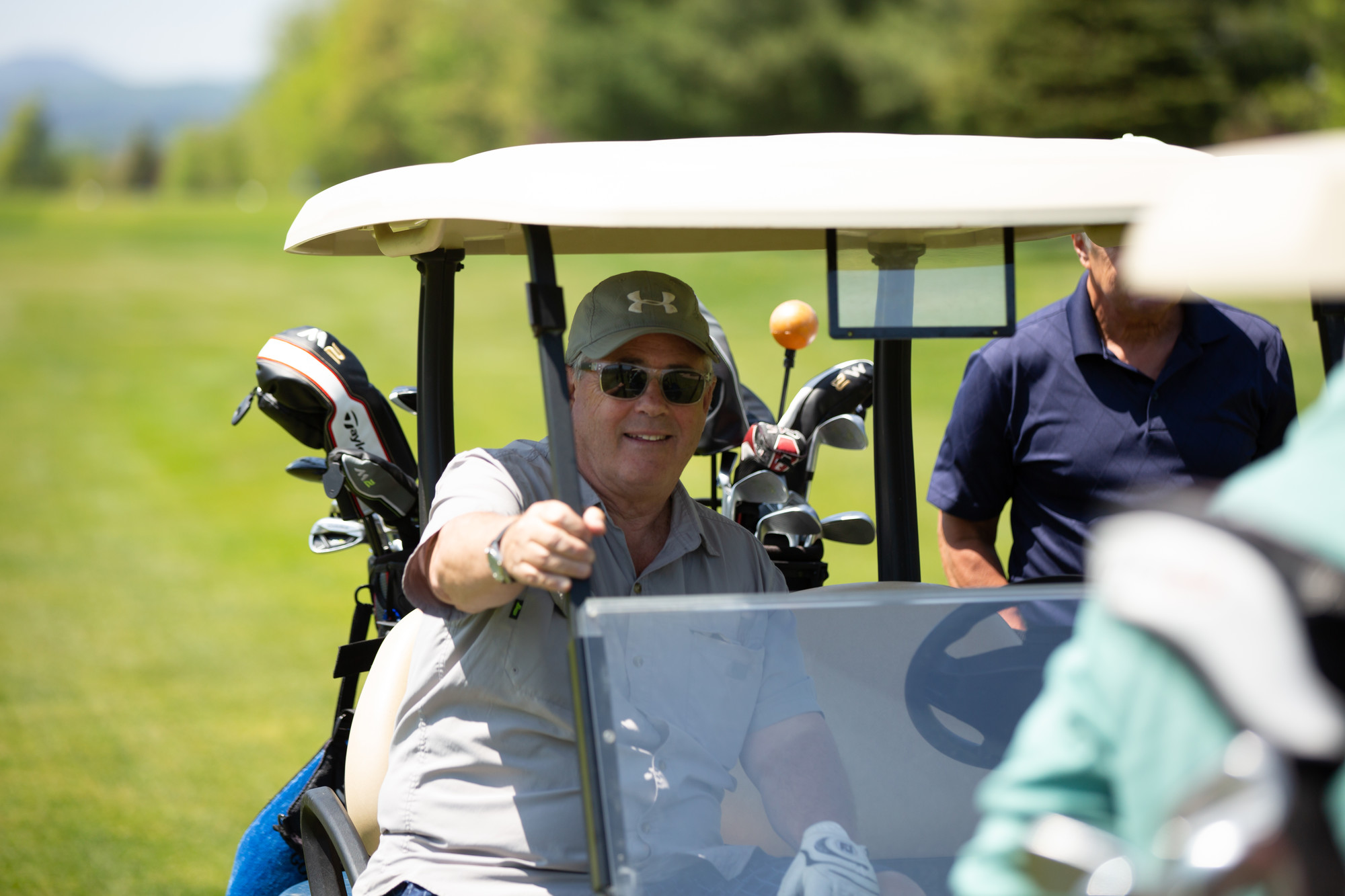 Golfer in a cart smiles at the camera.