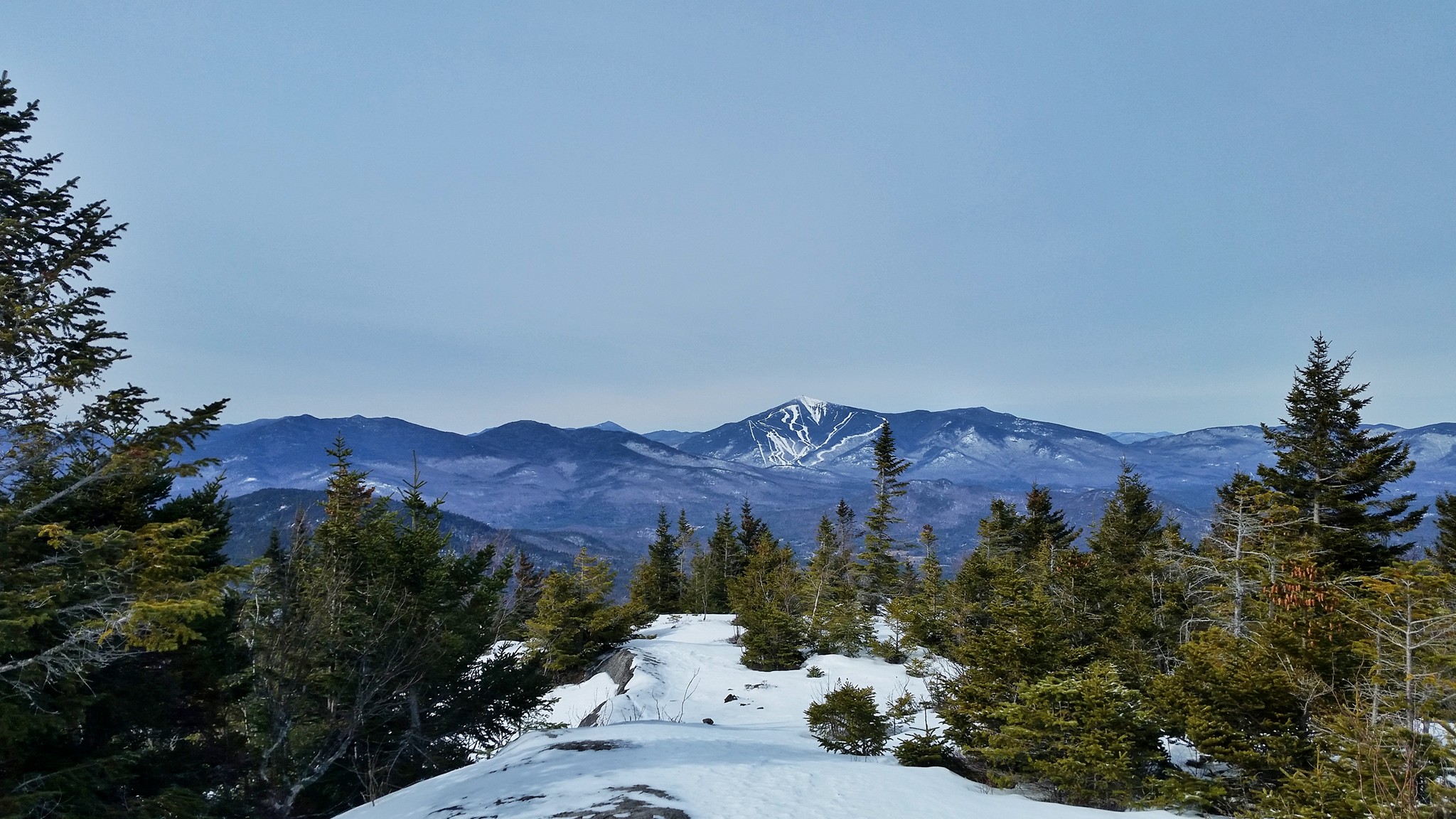 A winter view from a mountain summit with the ski trails at Whiteface visible in the distance.