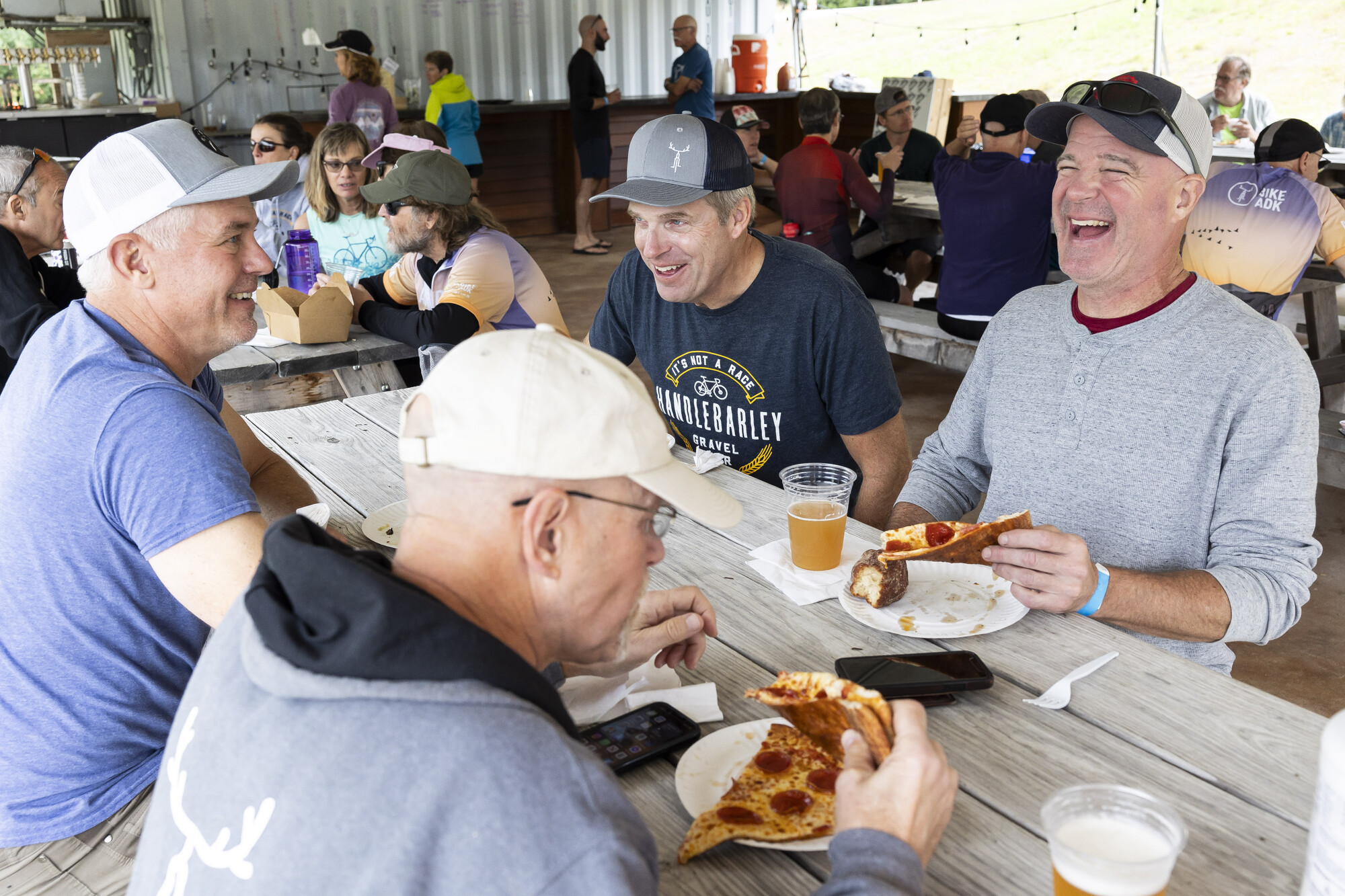 A group of men share pizza at a picnic table.