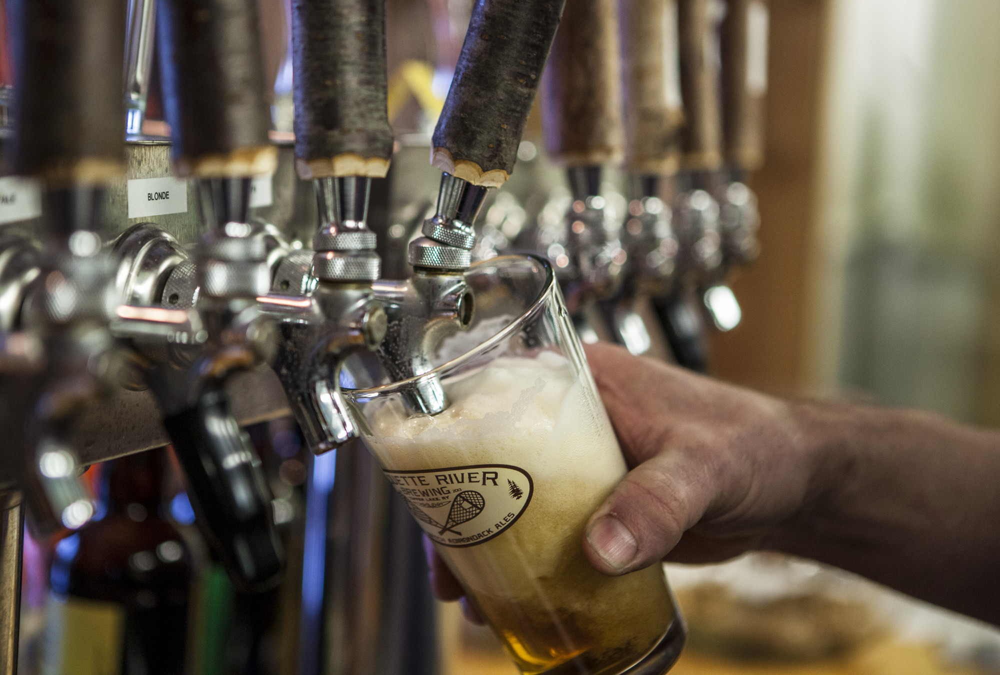 A beer is poured from a tap at Raquette River Brewing