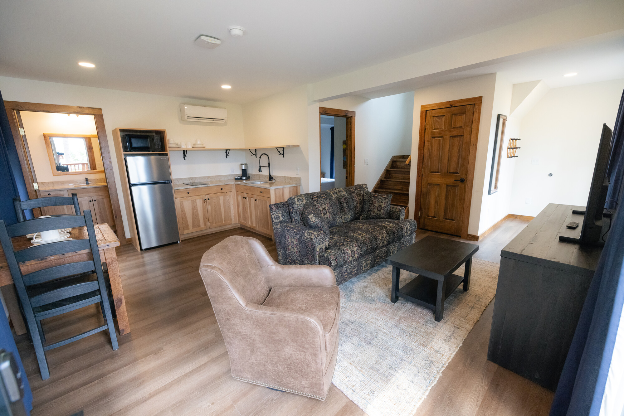 The interior of a spacious hotel room showing living and dining areas and mini kitchen.