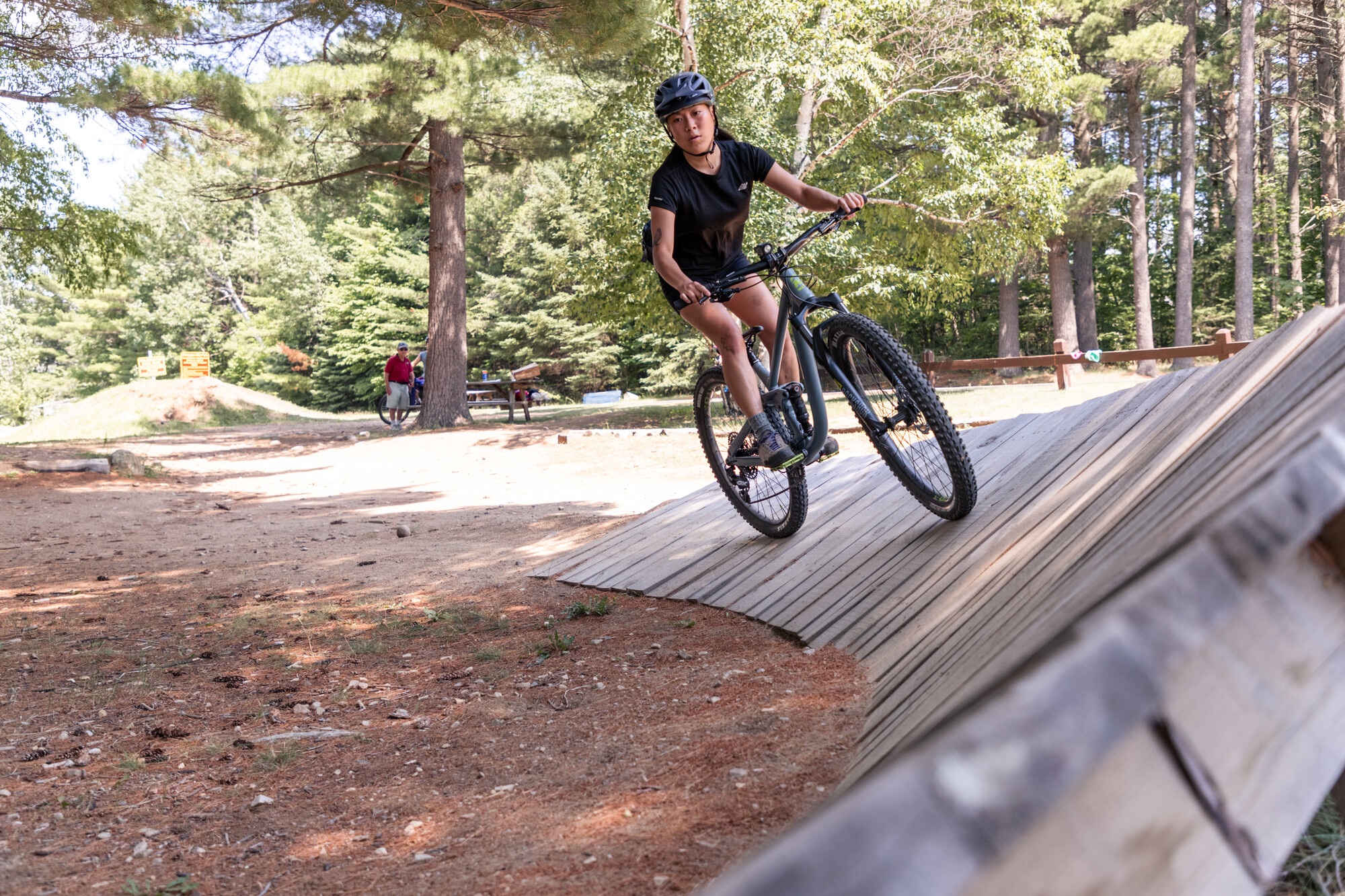 A cyclist rides on a curving wooden skills ramp.