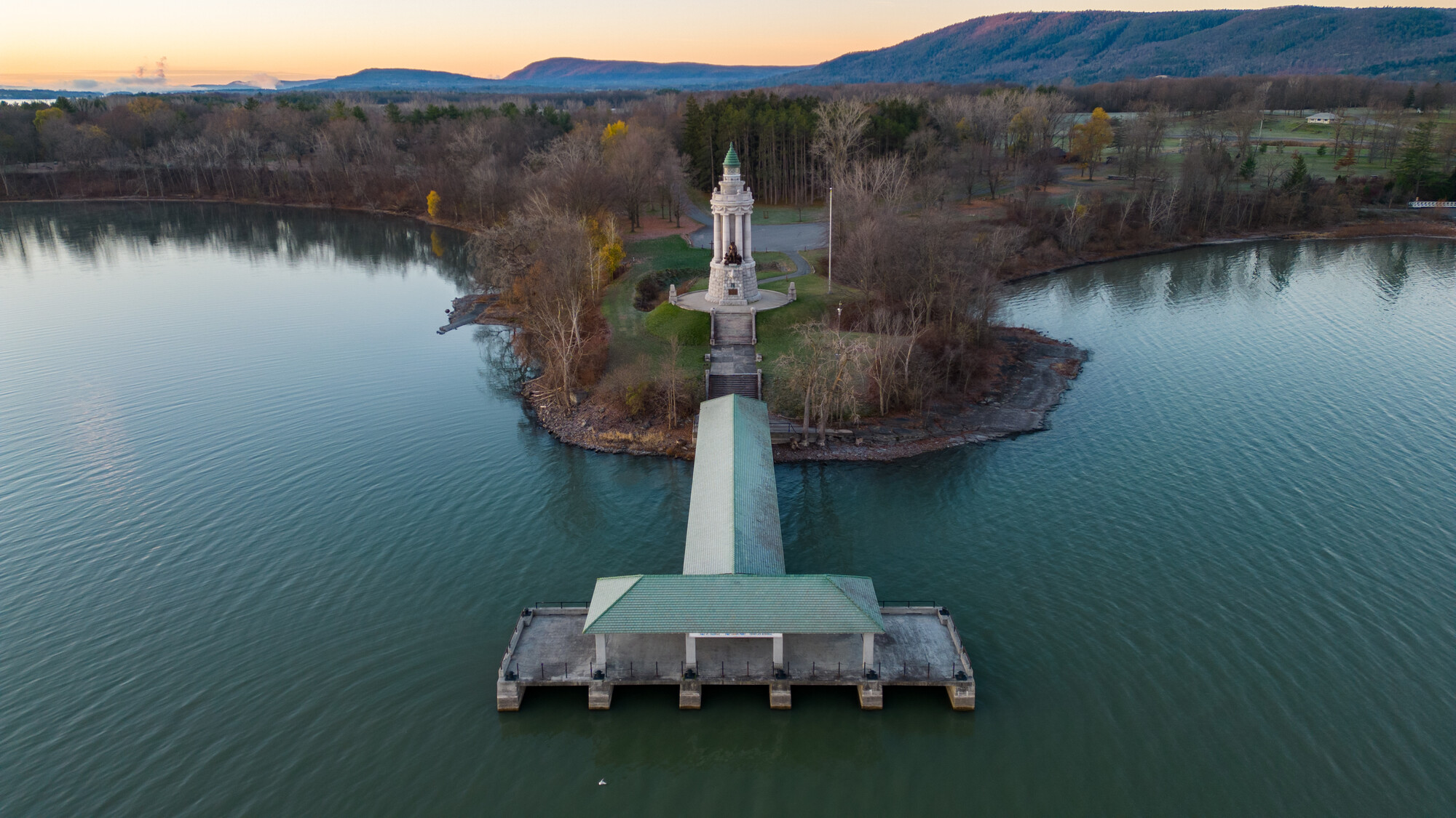 Aerial view of the Champlain memorial Lighthouse with mountain views in the background.