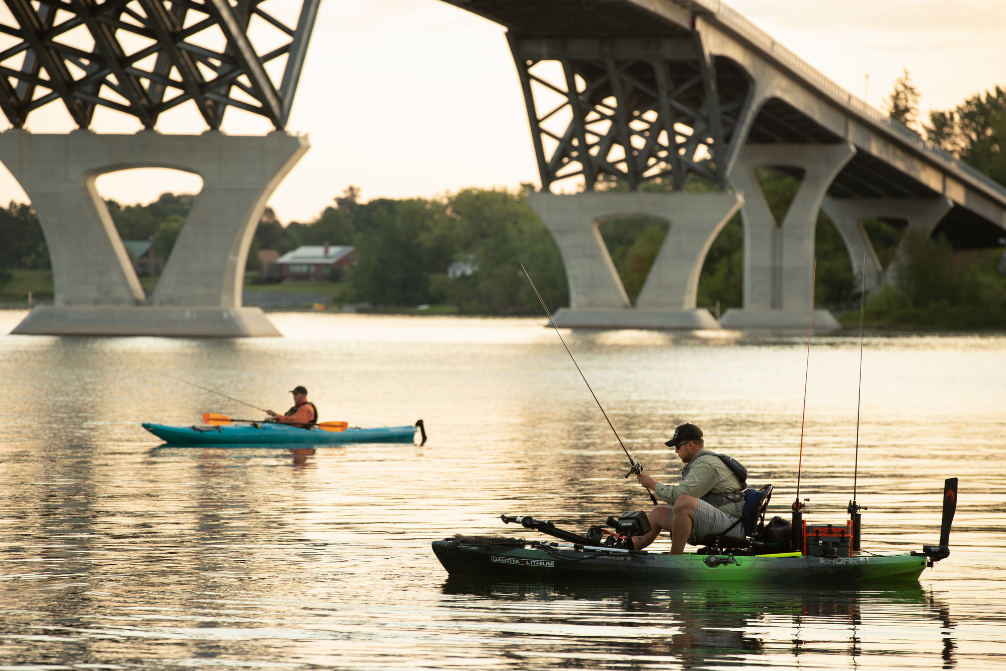 Two kayakers fishing near a bridge on Lake Champlain.