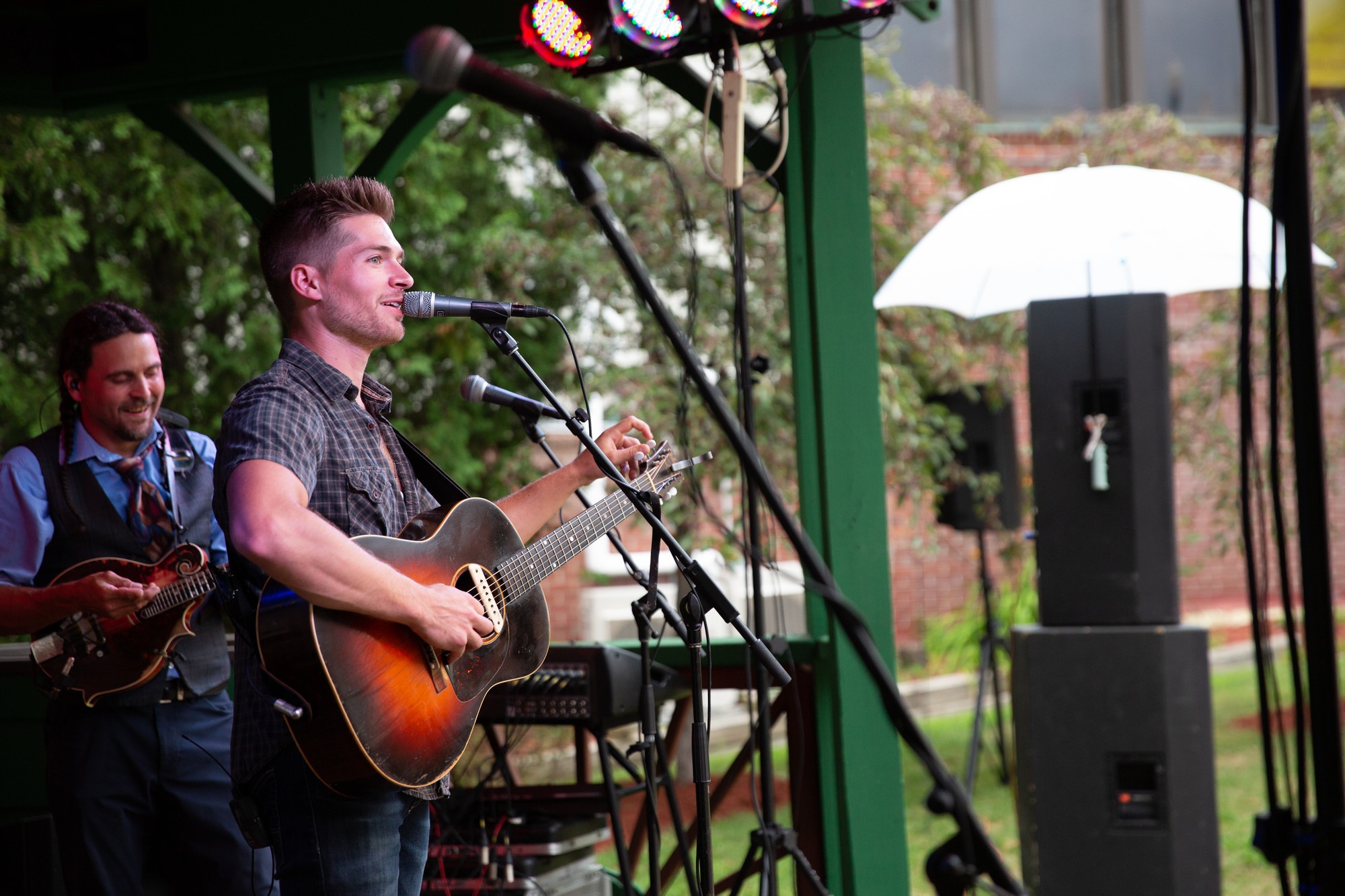A man sings on stage in a park