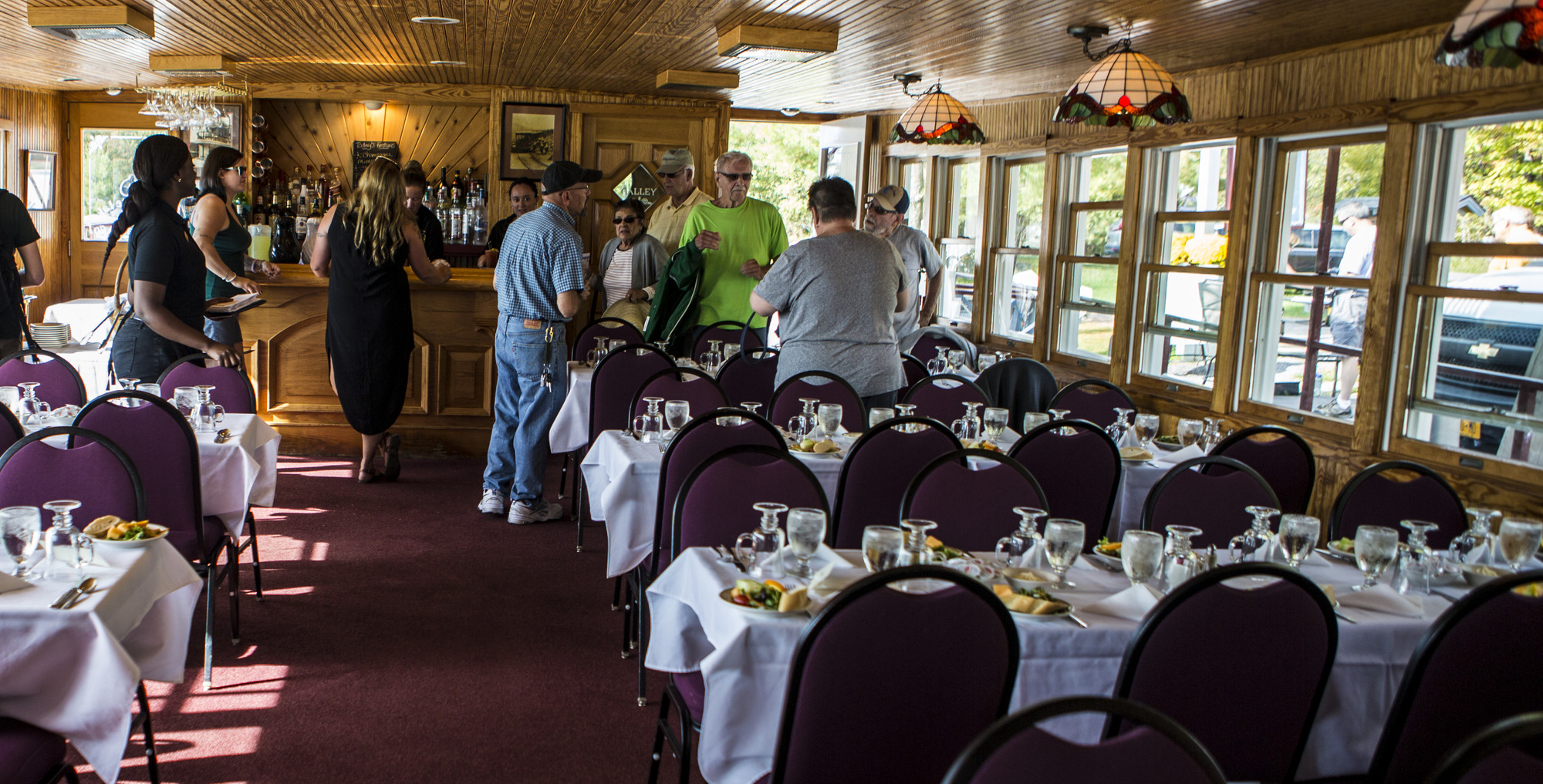 People having conversation in a dining room while others order from a bar