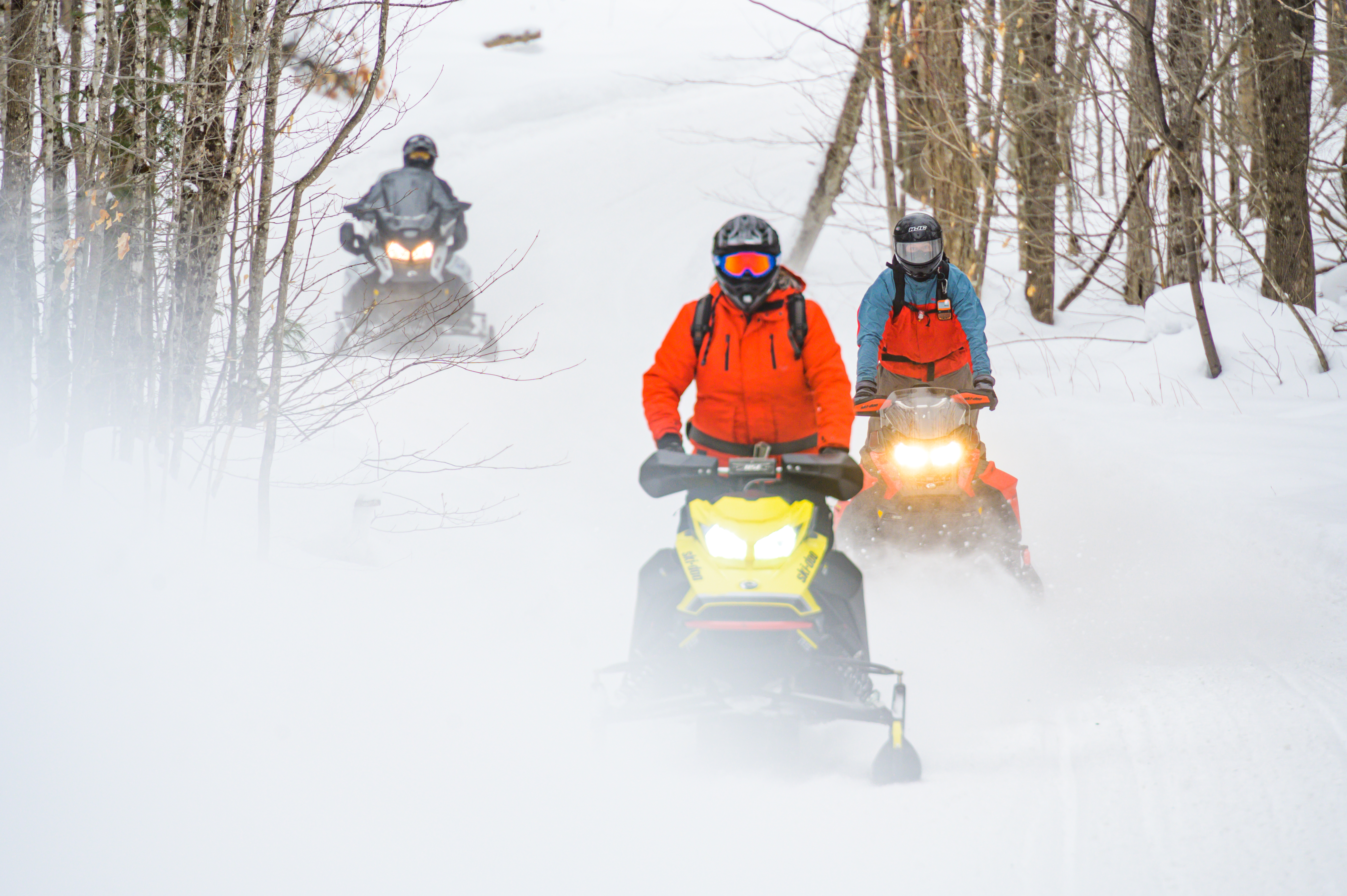 Snowmobilers heading down the groomed trail.
