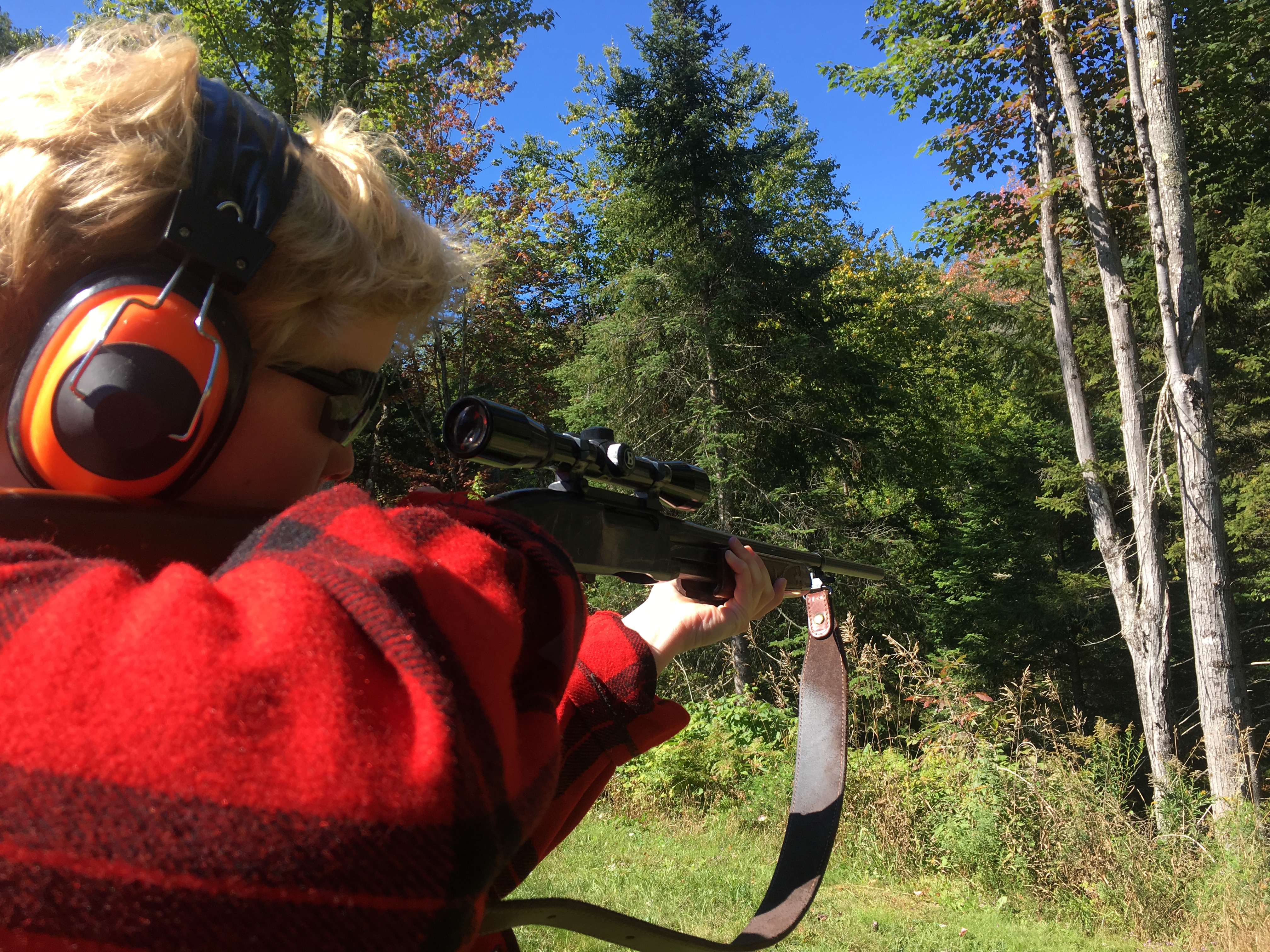 Young woman sigthing in her hunting rifle