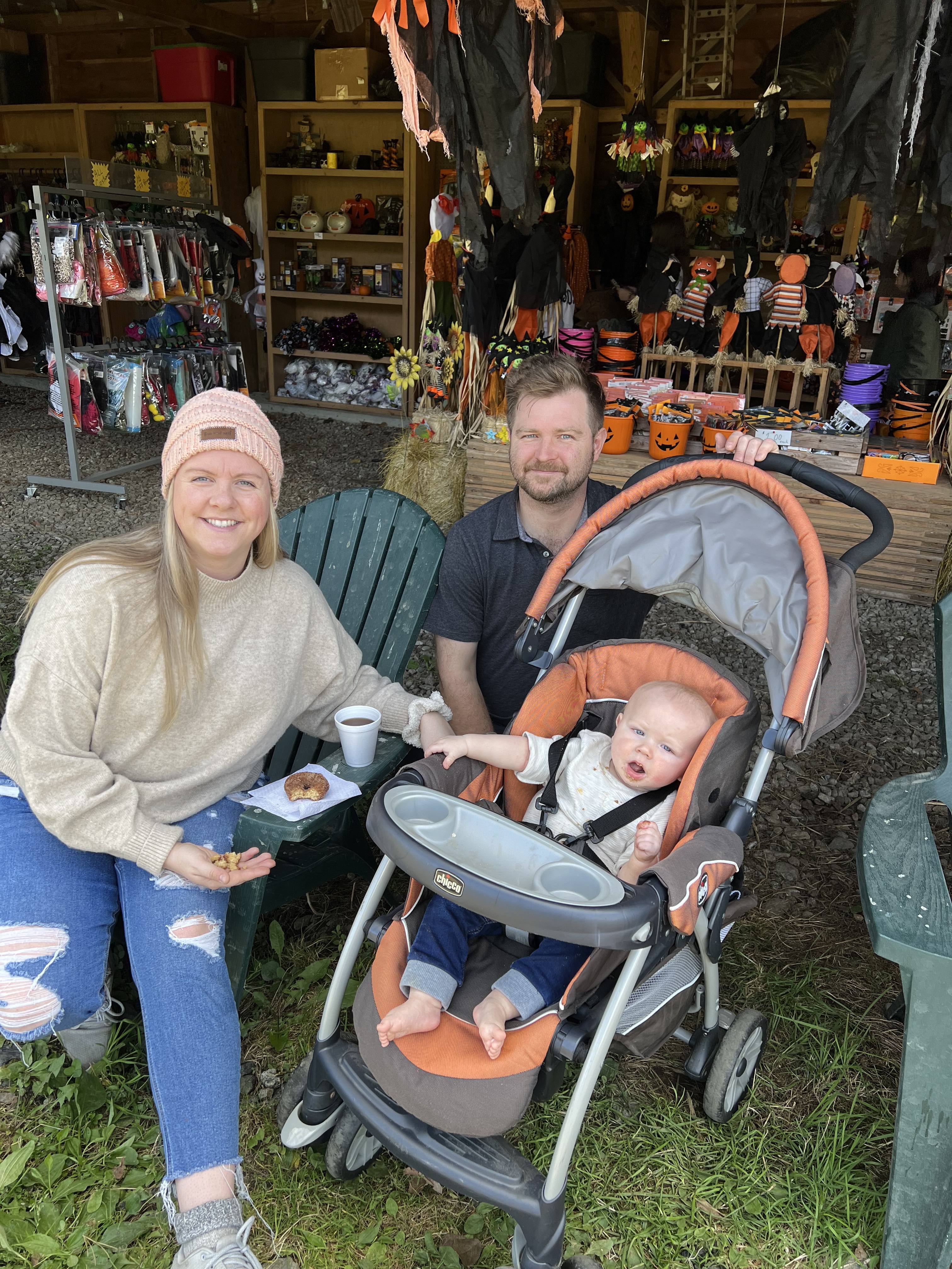 A woman, man and a baby in a stroller pose with cinnamon sugar donuts.