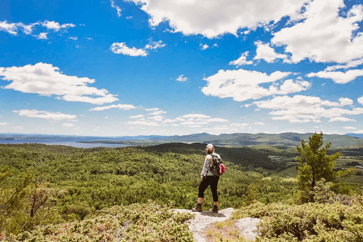 A hiker standing on a mountain with a view of the lake and other mountains