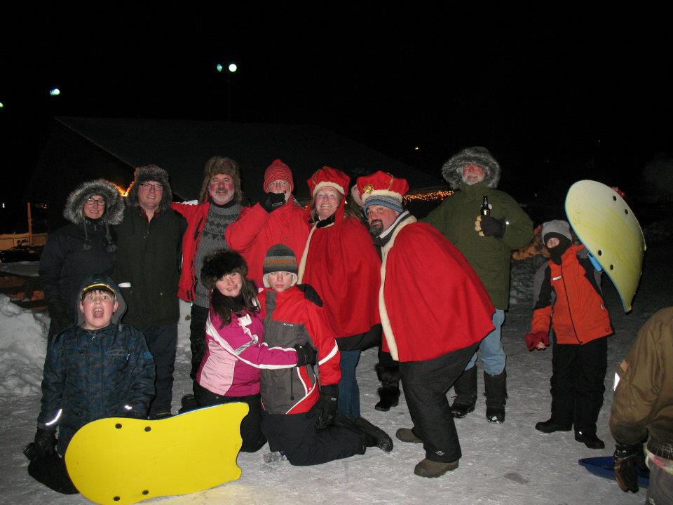 A group of people dressed in winter clothes and some in royal robes smile during winter carnival. 