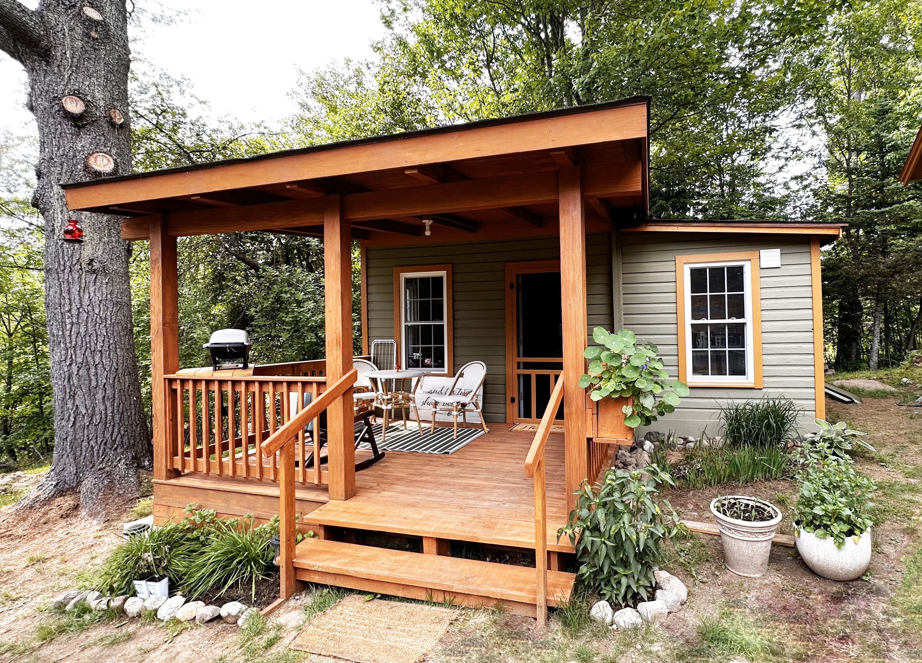 A small, olive colored cabin with a front porch.