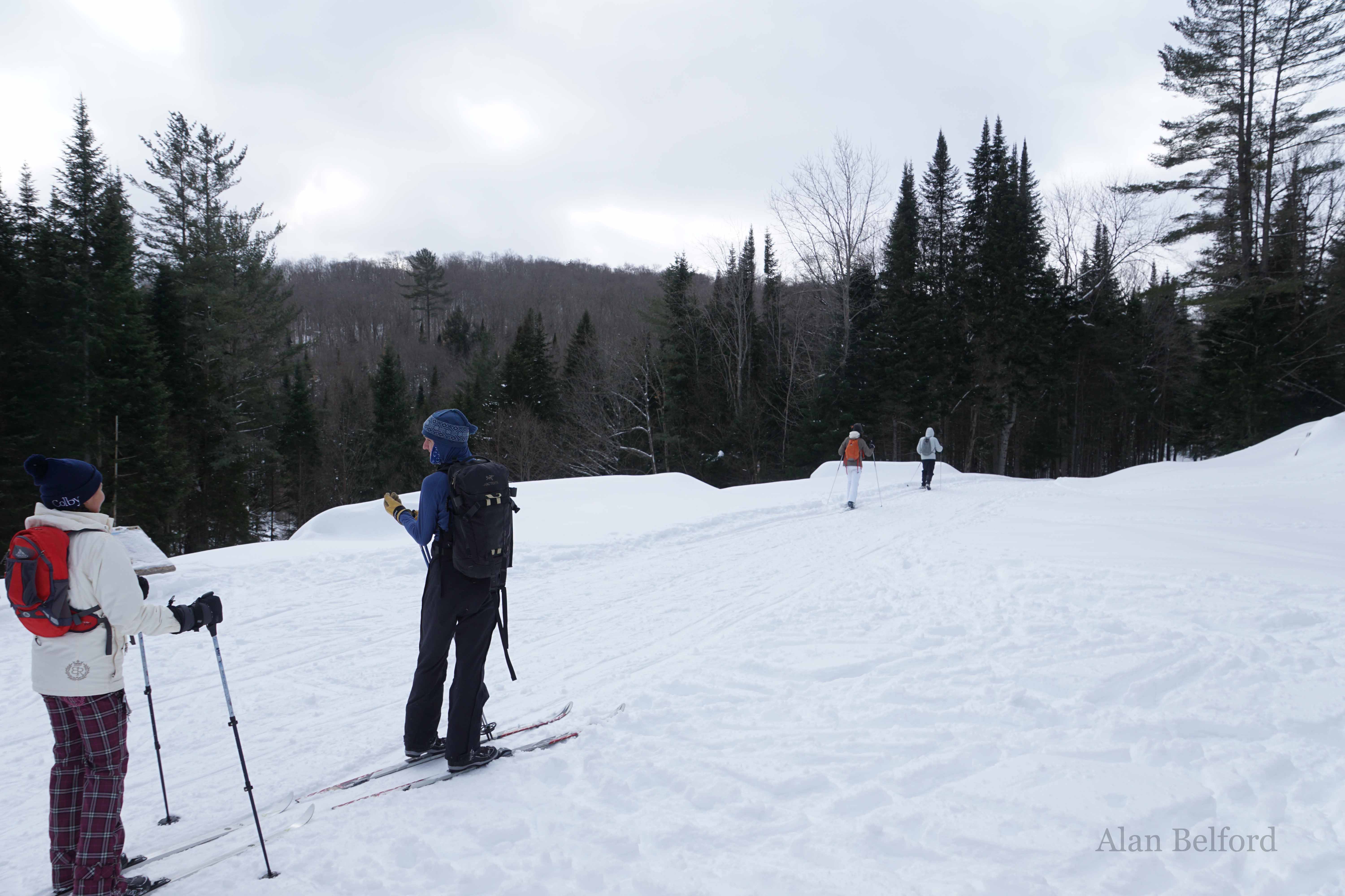 A pair of skiers pause on their return trip to look at the farm complex while others continue on to the parking area.