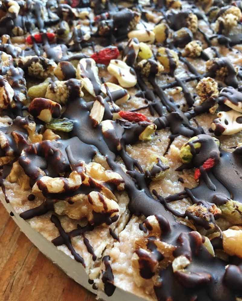 Close up of vegan cheesecake topped with chocolate and nuts.