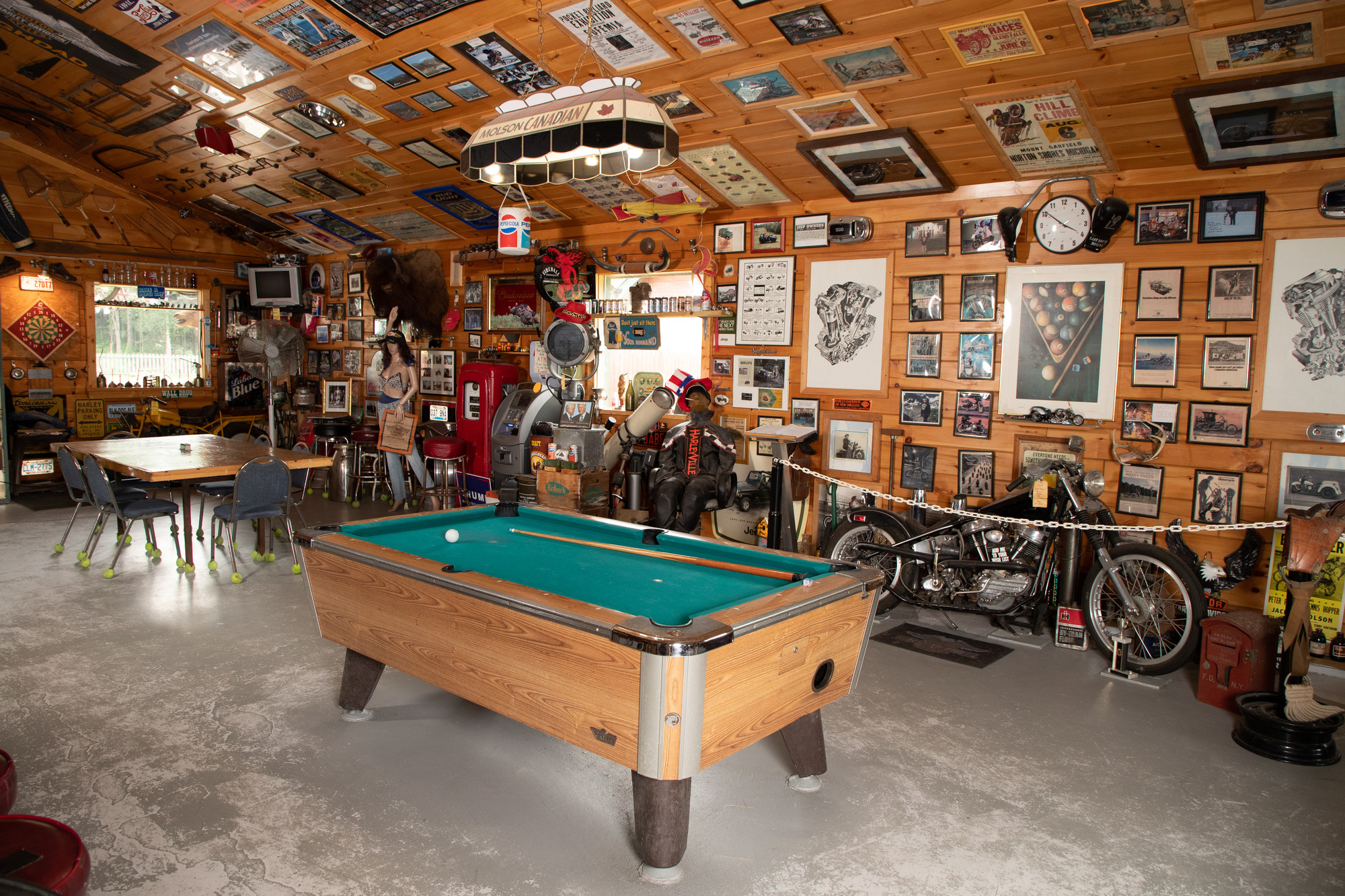 A motorcycle-themed restaurant is filled with memorabilia on the walls and ceiling, plus a pool table.