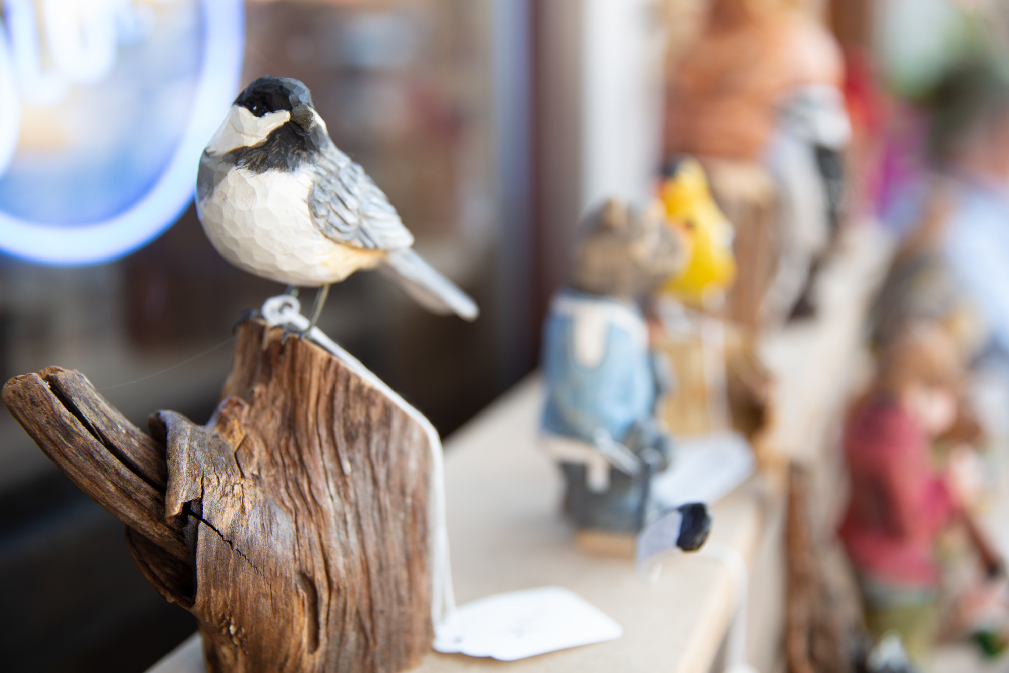 A Black-capped Chickadee carving by Mark A. Paul. A wooden Black-capped Chickadee on display at an art event.