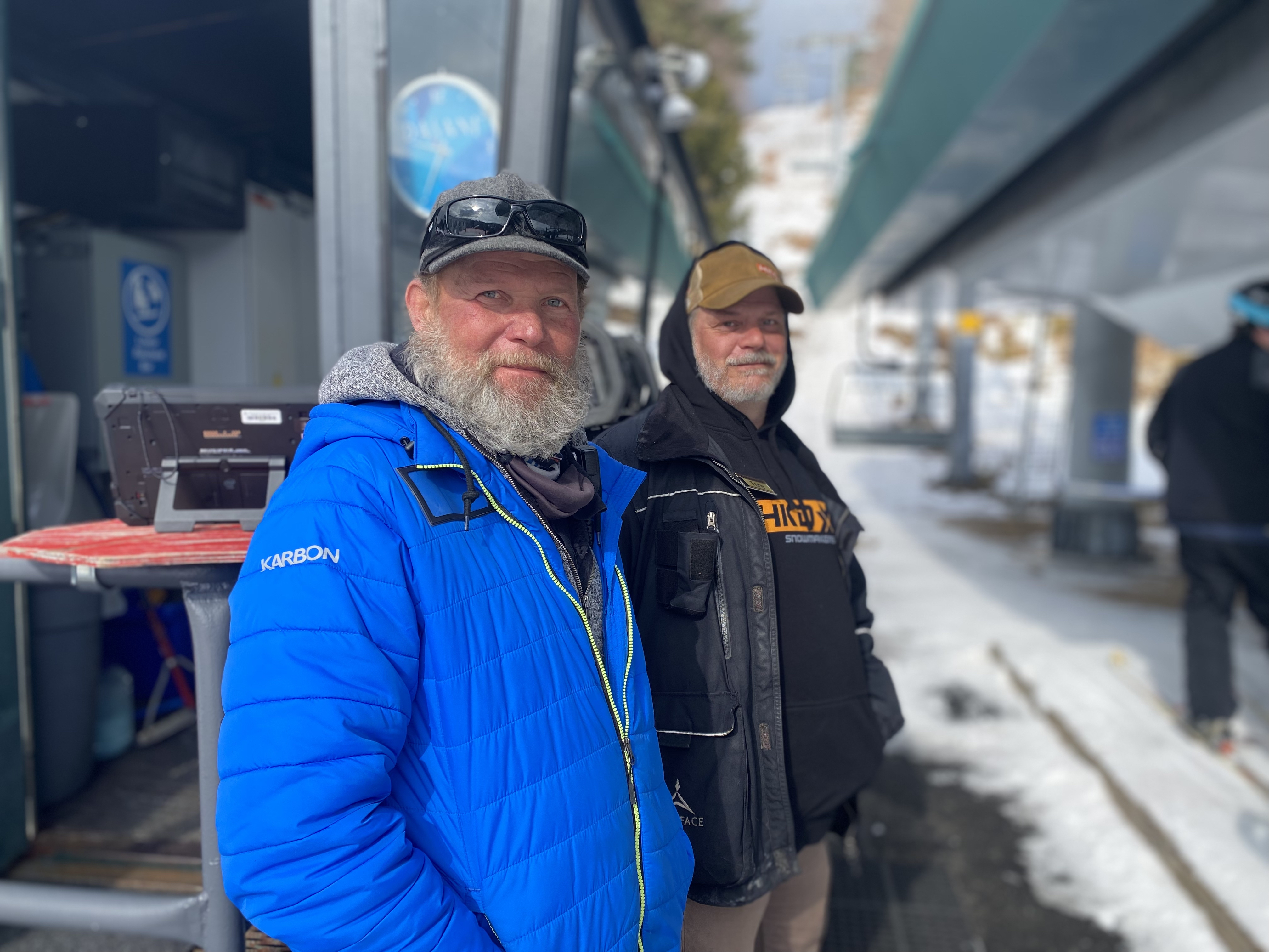 Two lift attendants enjoy the sunny morning at the mountain